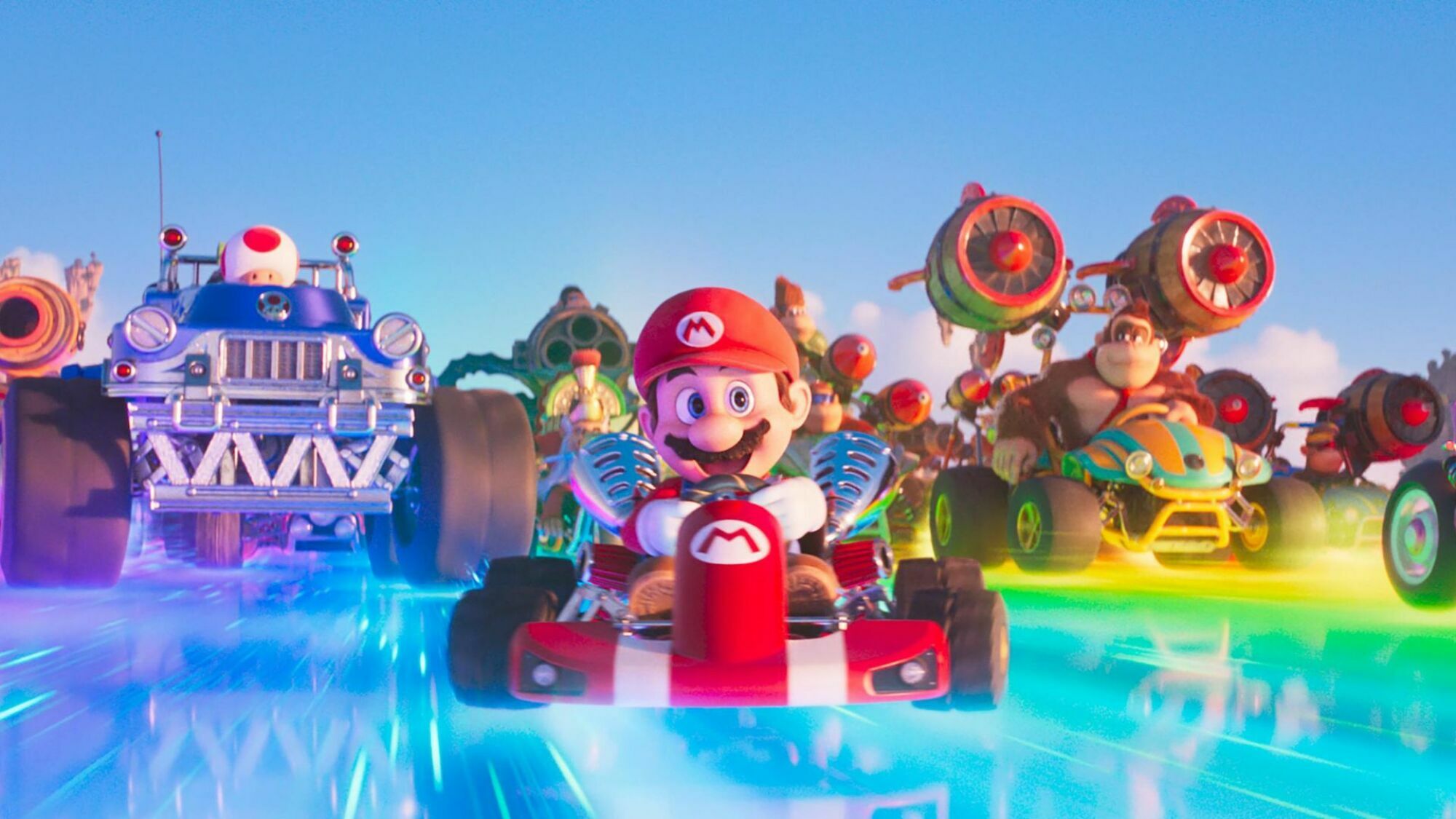 Mario characters race down Rainbow Road in go-karts.