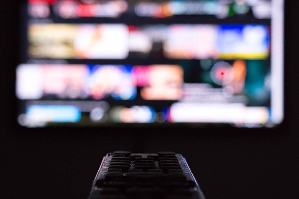 a remote control is held up to a tv, the screen of the tv is colorful but blurry 