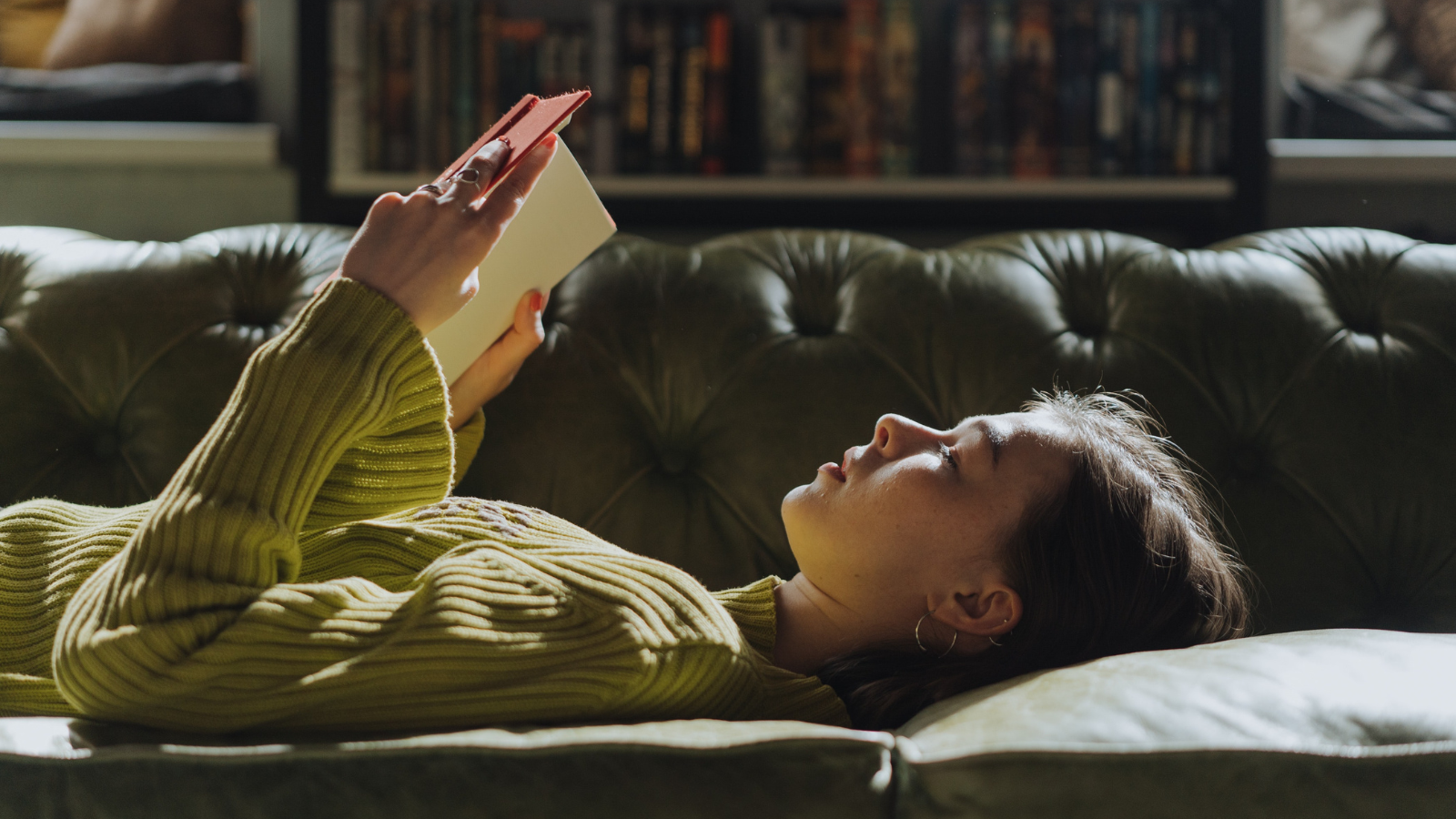 woman reading book on couch