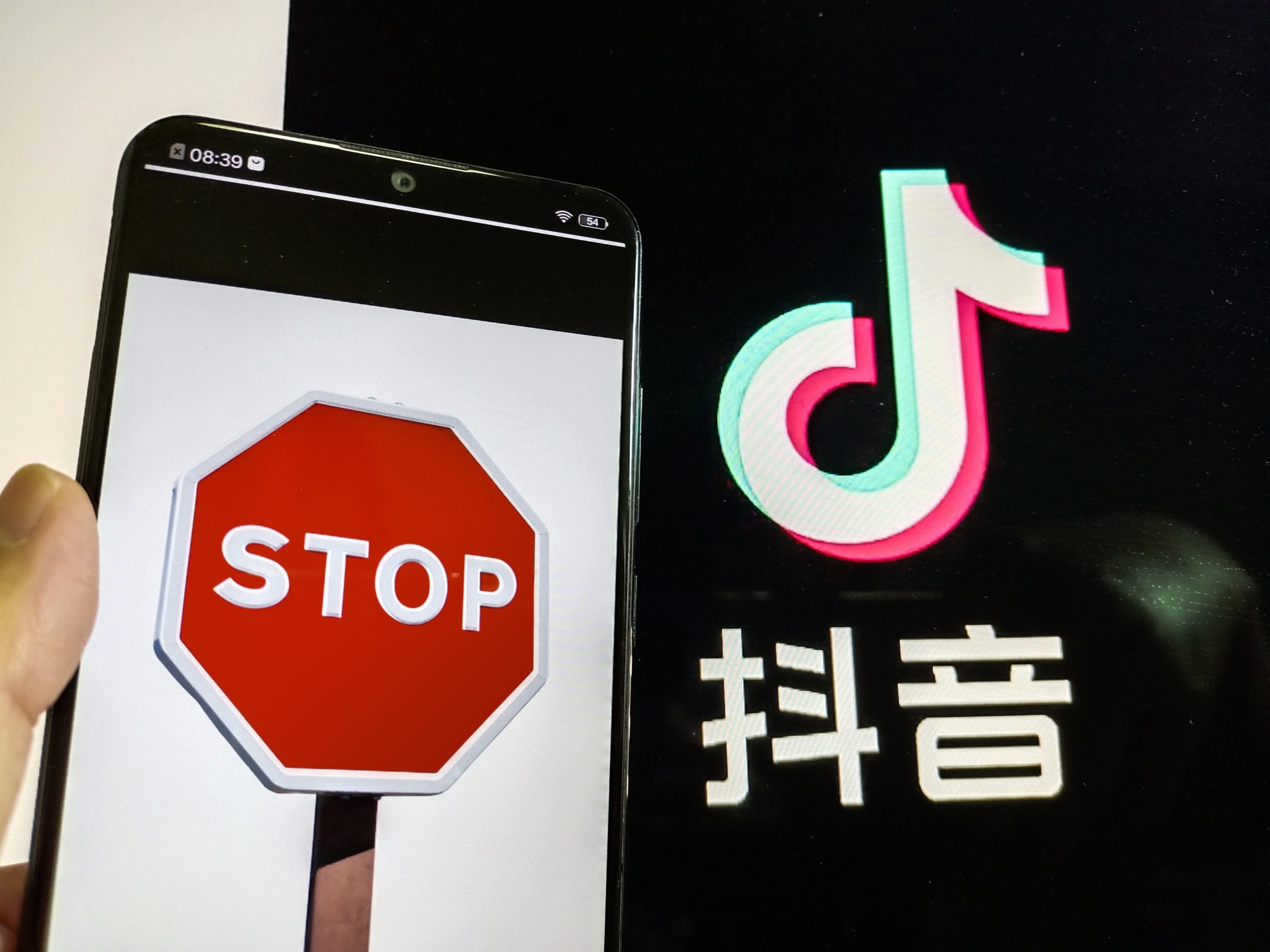 A stop sign on a phone screen and the TikTok logo with some Chinese characters