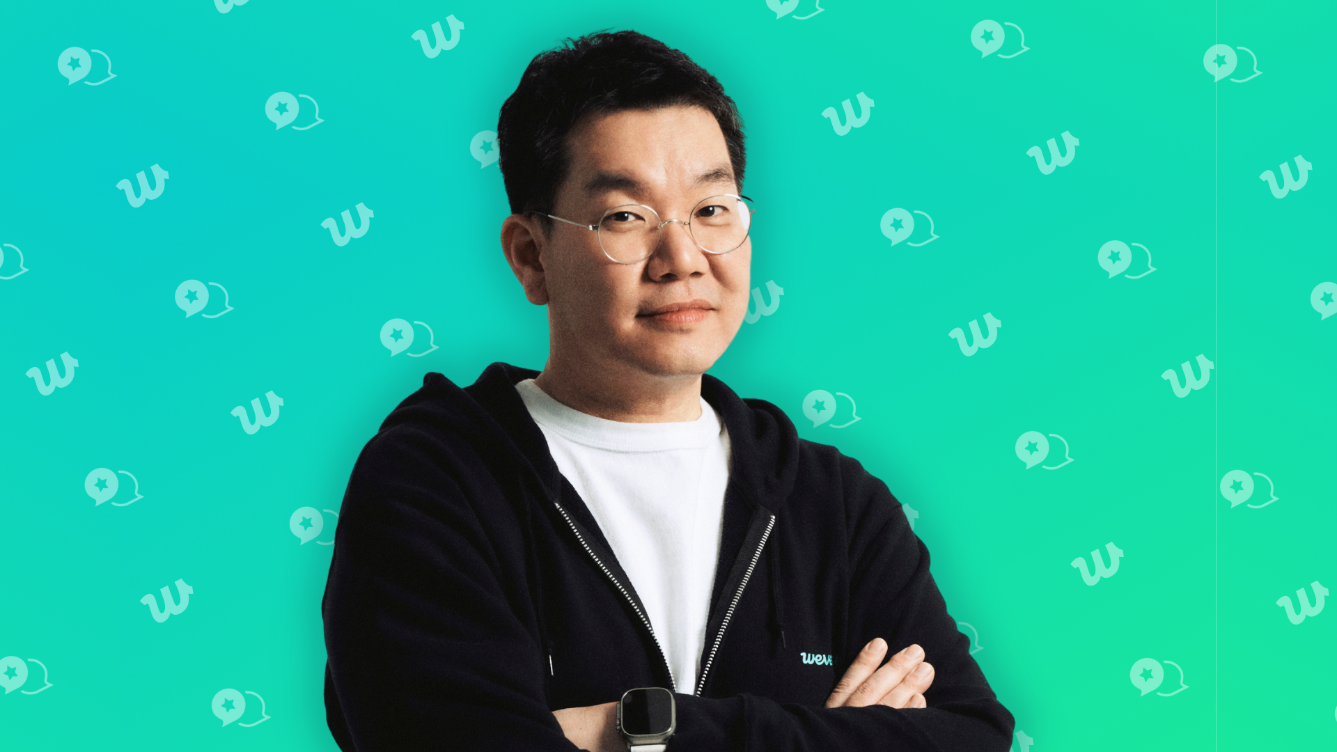 Weverse President Joon Choi from the chest up, wearing a black hoodie. The background is green, with a pattern of the weverse logo