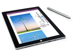 tablet is sitting flat on a white surface next to a stylus pen