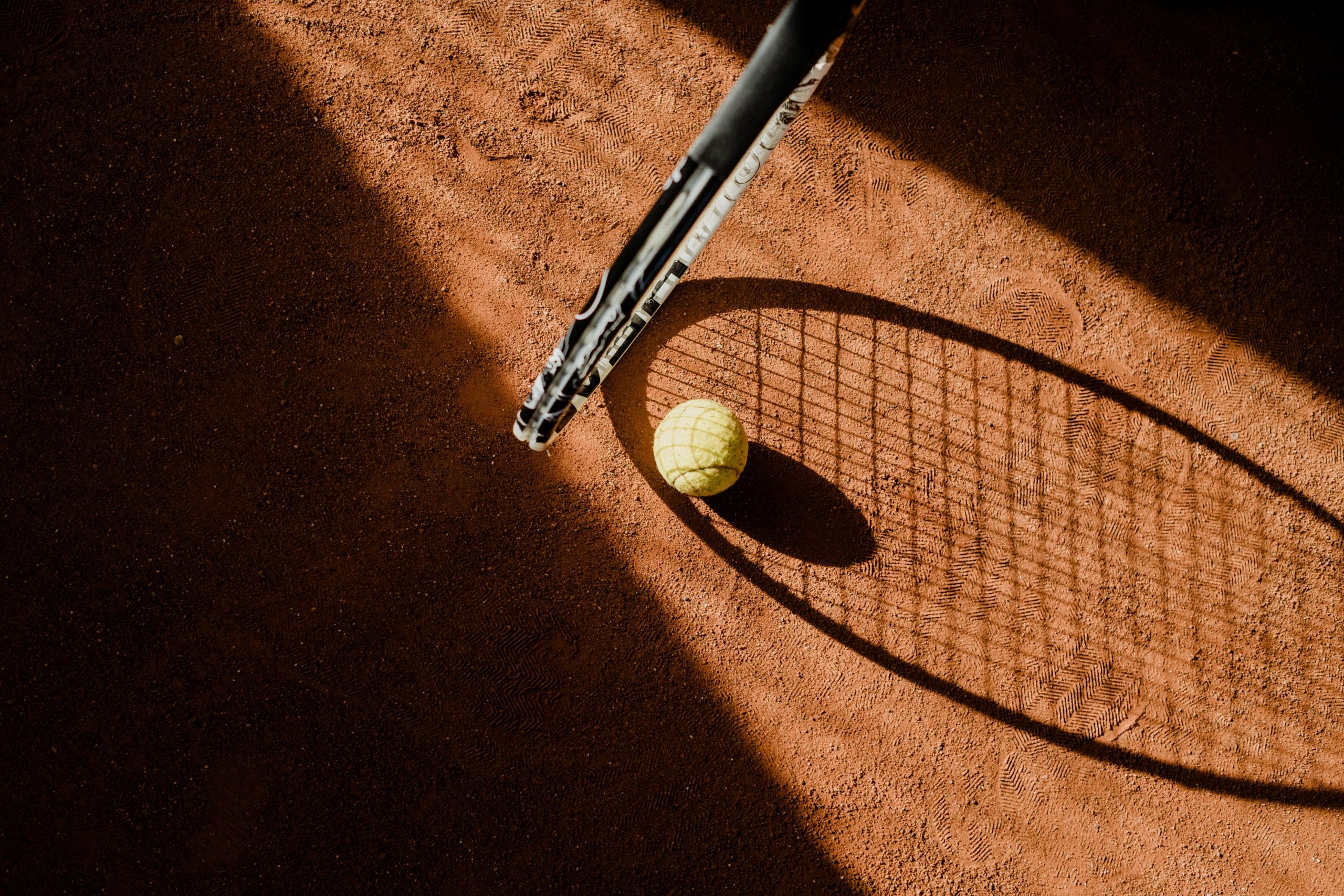 Tennis racket and ball on clay court
