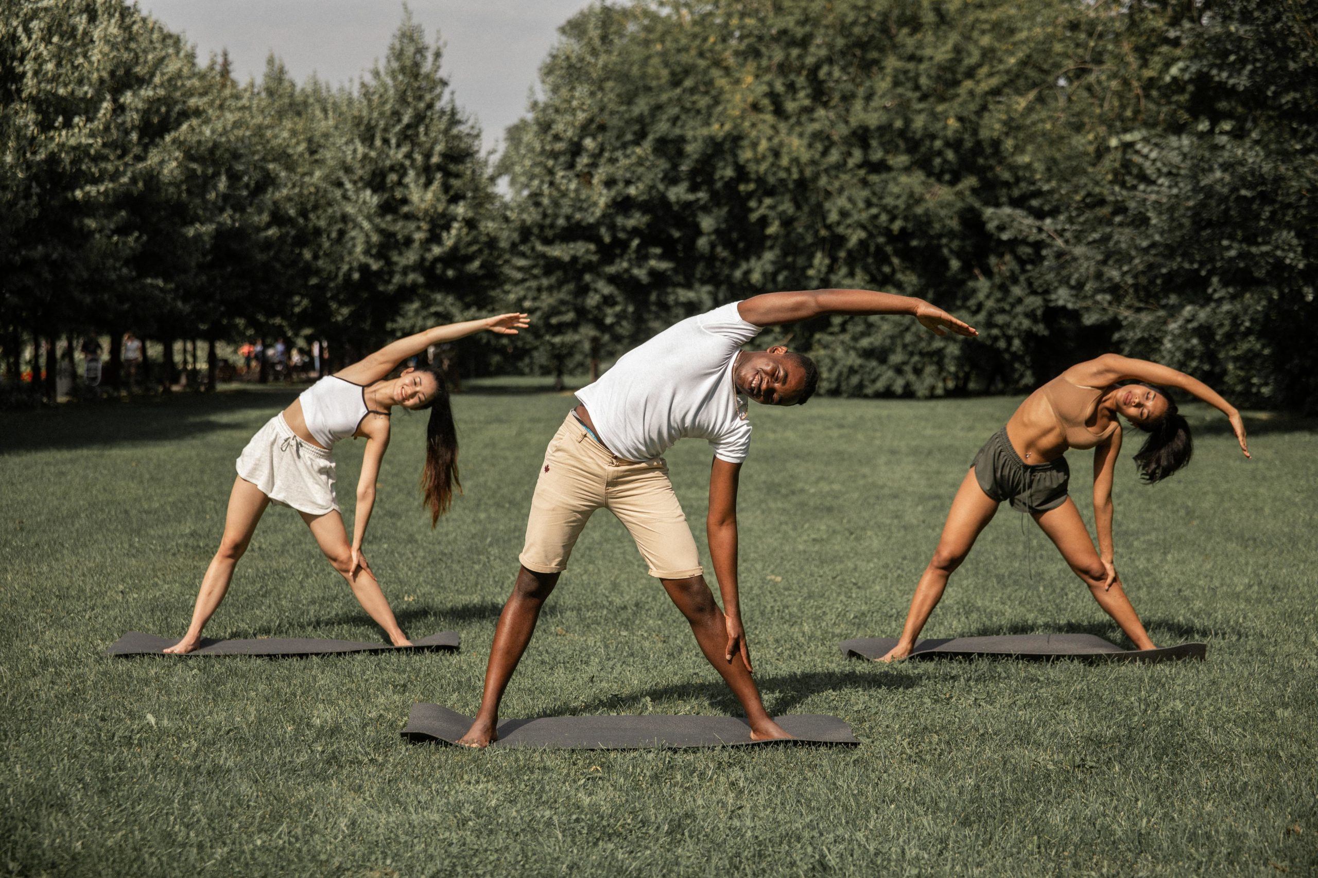 Three people stretching outdoors.