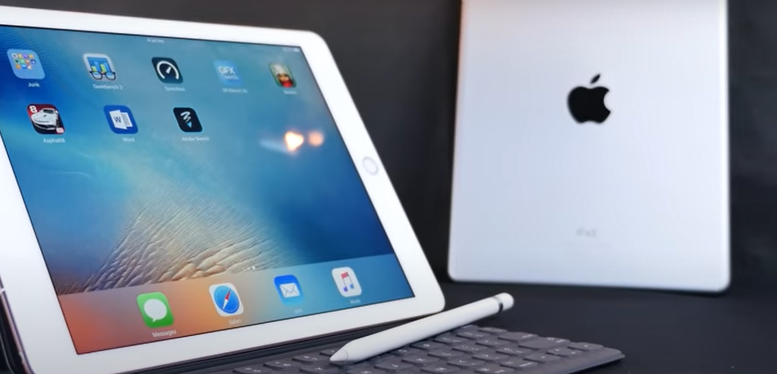 two ipads, one silver, one pink, against a dark background