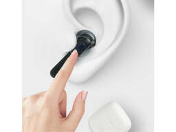 Hand touching an earphone in an ear
