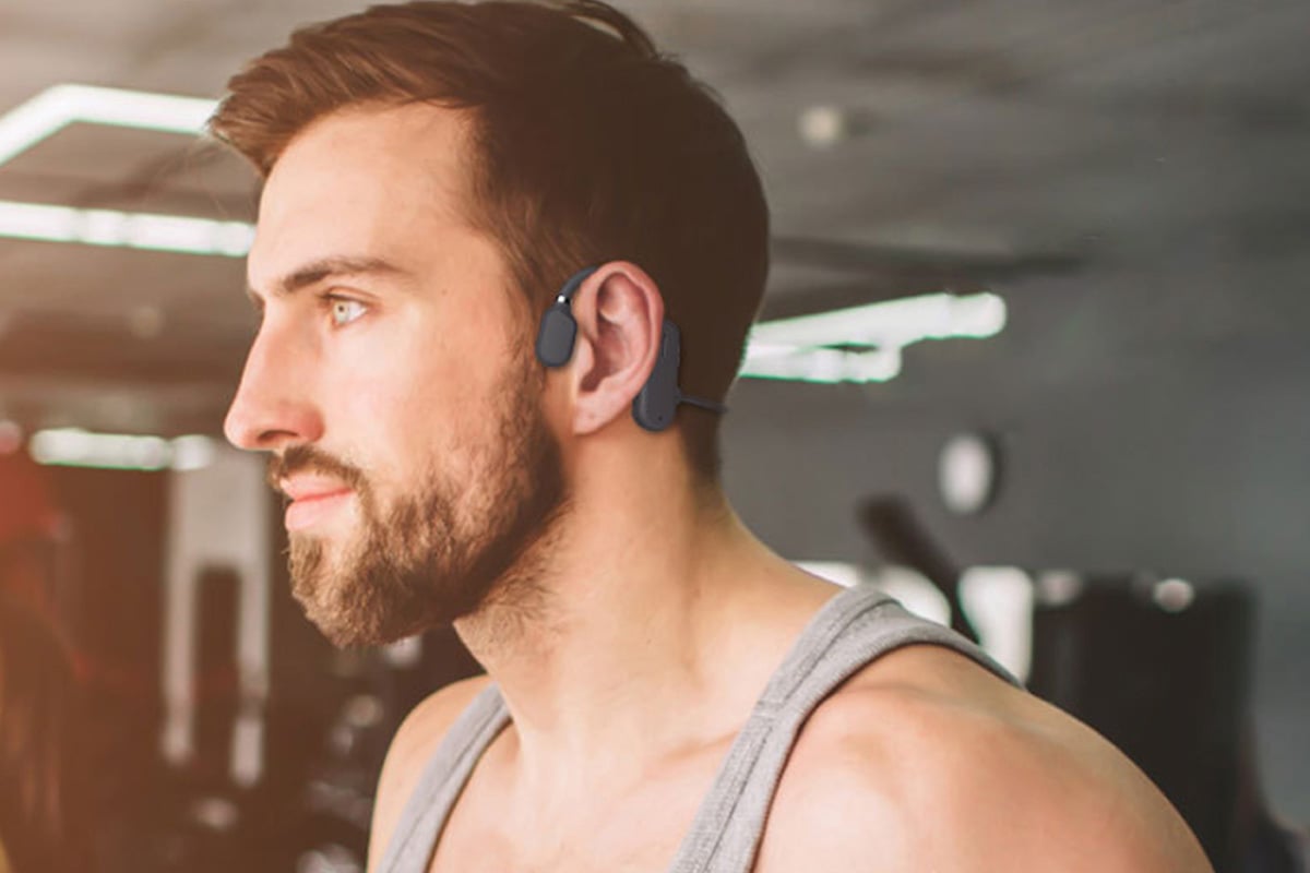 Man in profile wearing open-ear headphones.