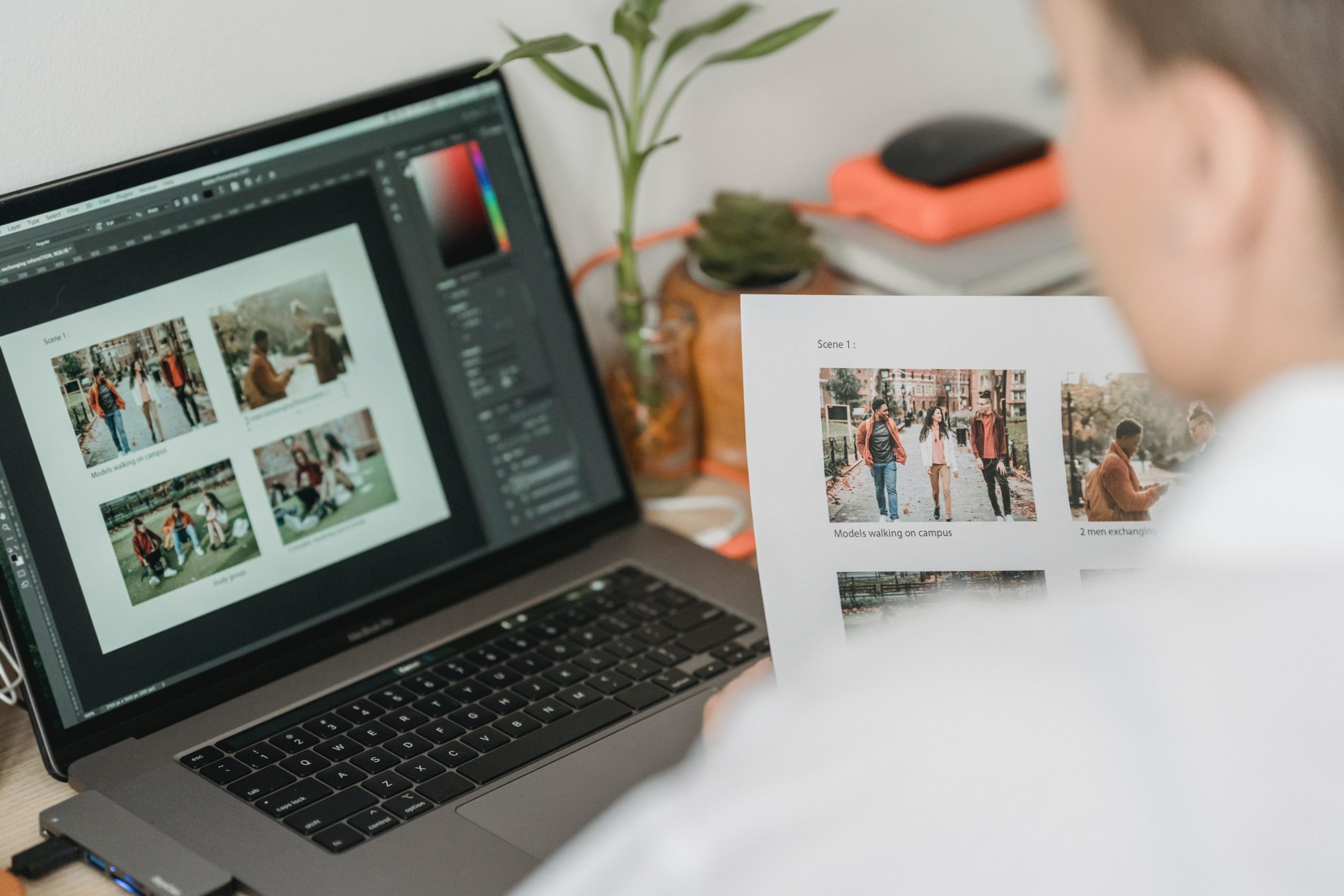 Person holding photos in front of a computer