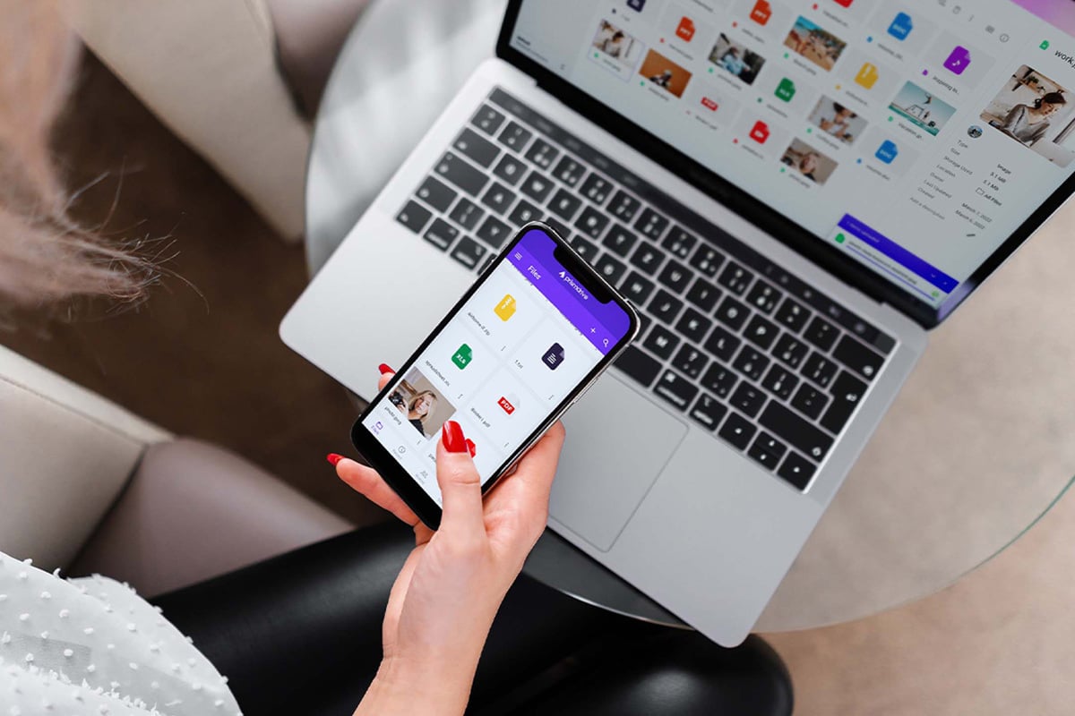 person holding phone in front of a laptop