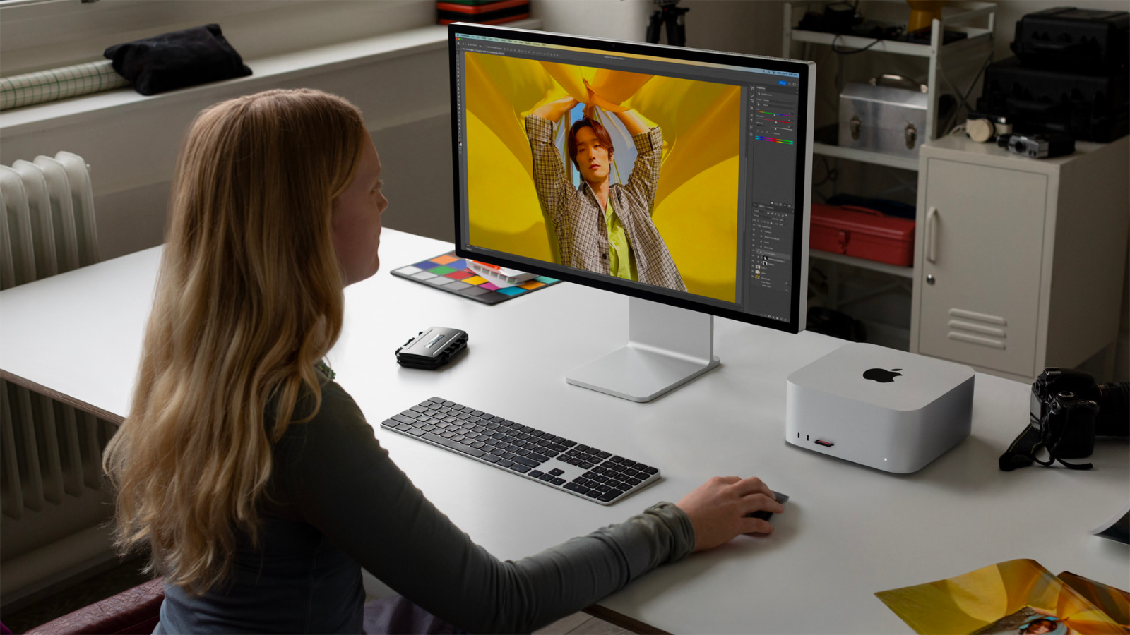 a woman sitting at a workstation using a display hooked up to a mac studio