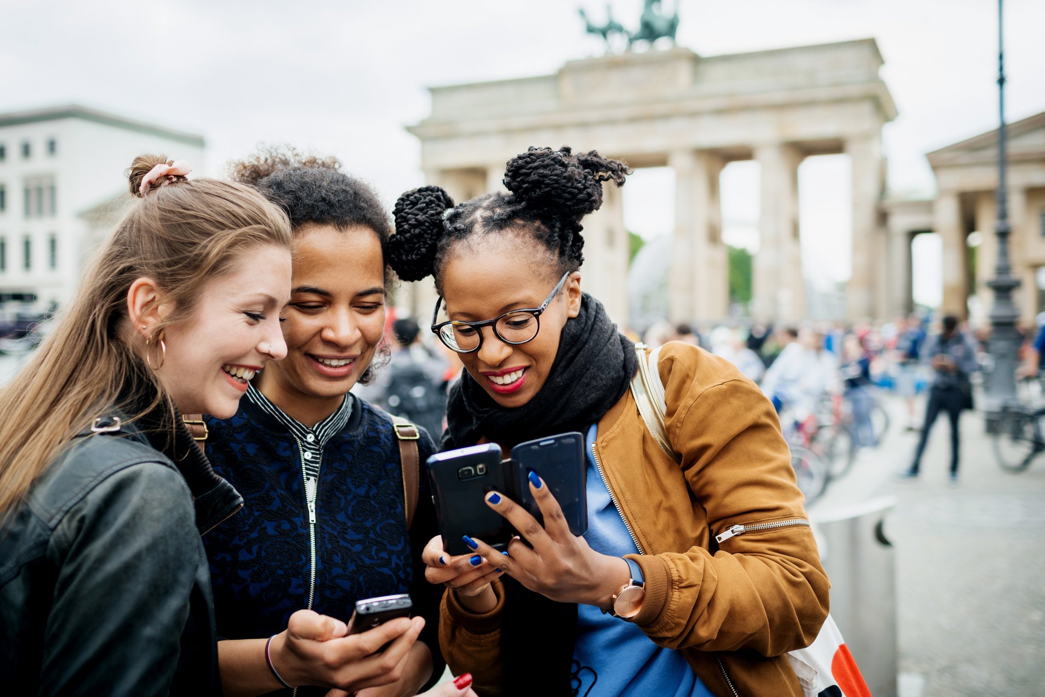 A group of friends traveling together stop to look at their phones.