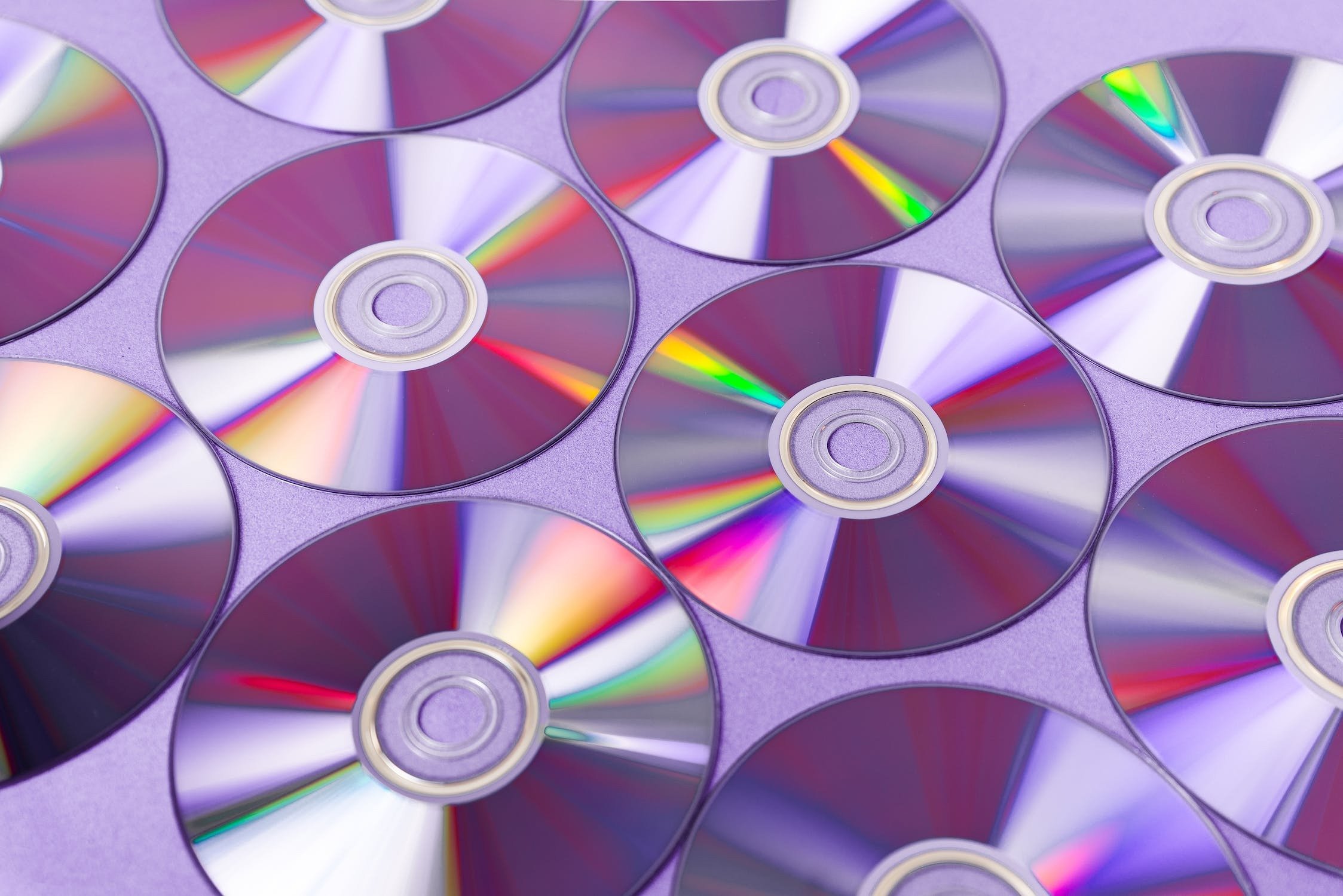 Many DVDs lined up in a pattern over a purplish background