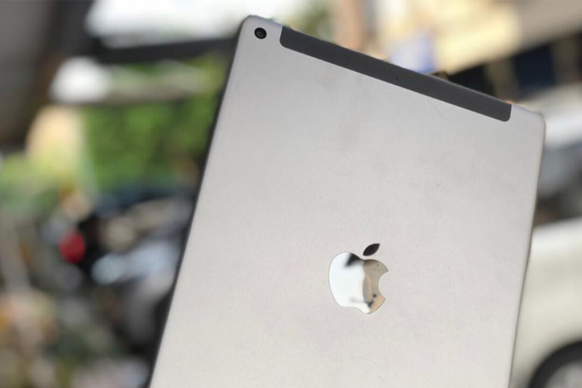 the Apple iPad 6th-gen shown in a light grey color on a blurred background