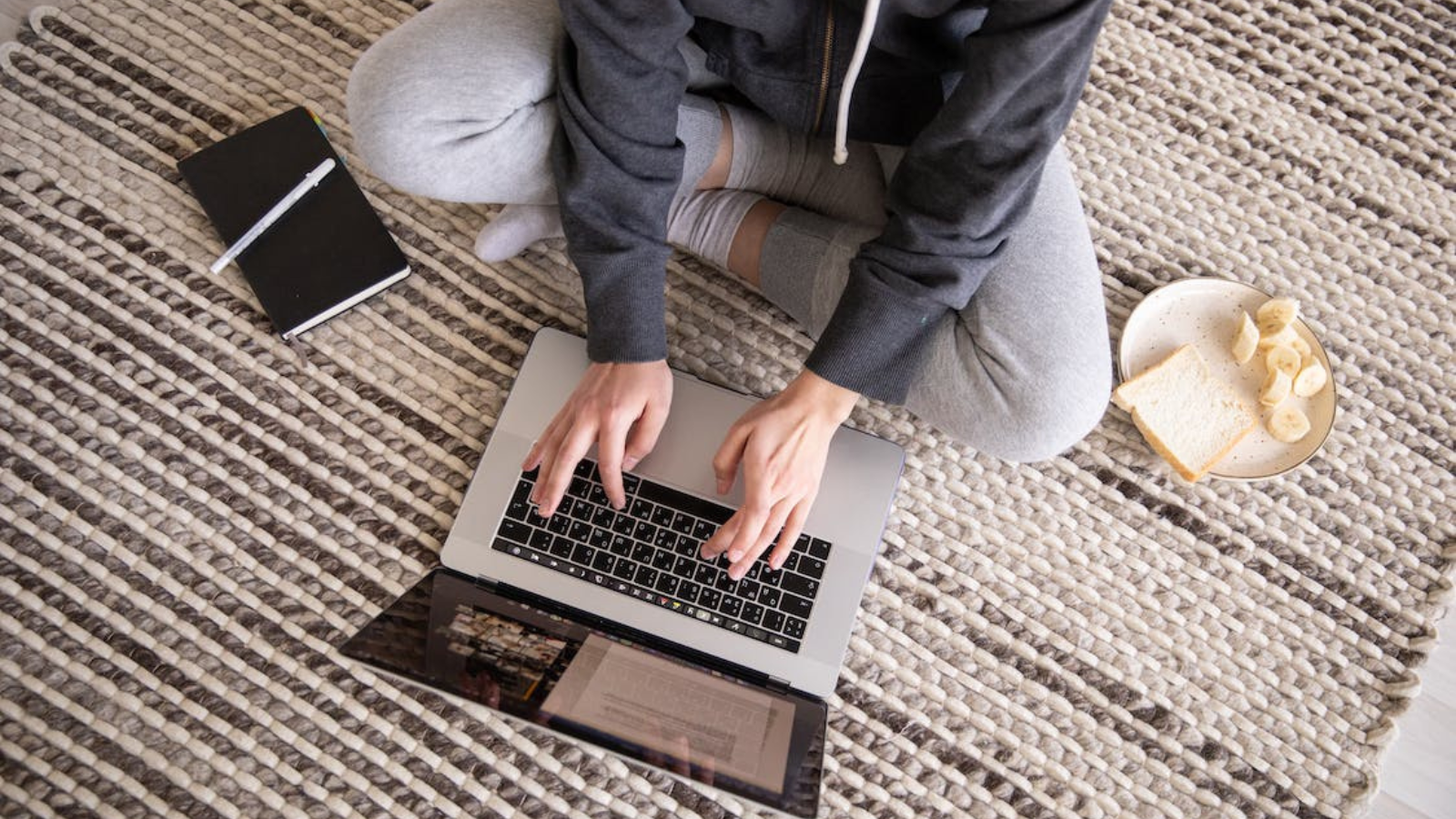 woman sitting on ground working on macbook air