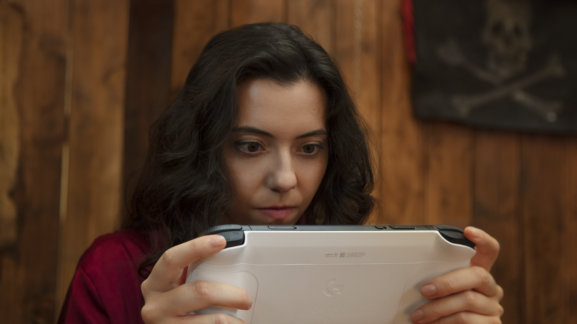 Woman holding the Logitech G Cloud gaming console in her hands while staring intensely at it 