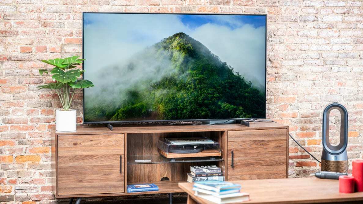 The 50-inch AU8000B Smart TV from Samsung standing on top of living room shelving surrounded by a plant and accessories