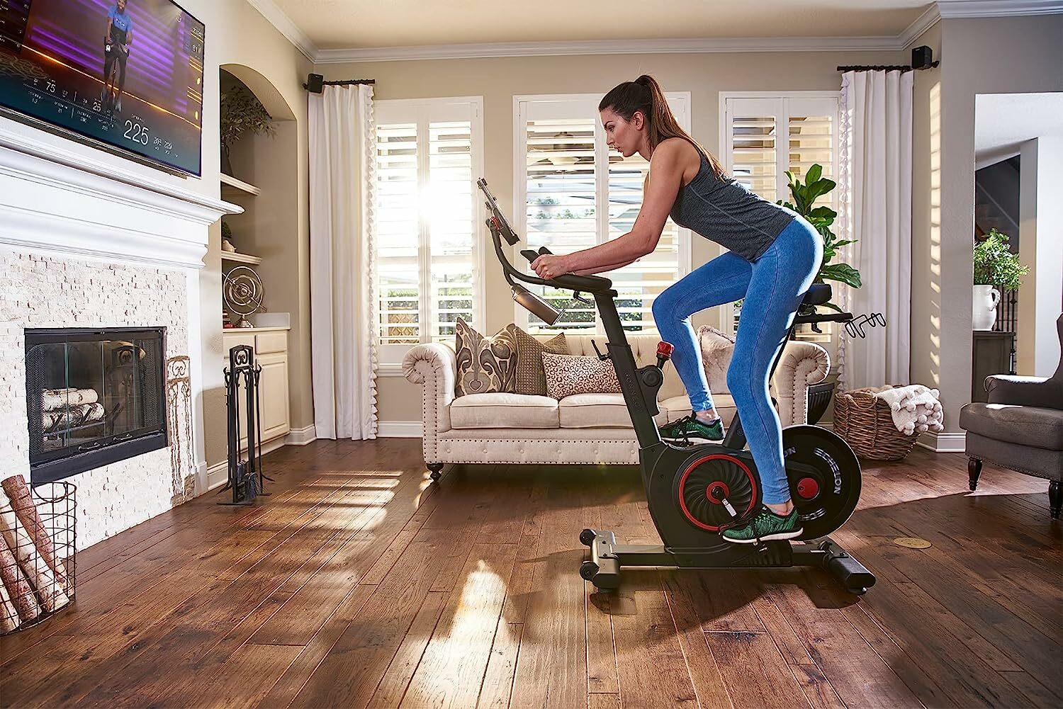 Person riding exercise bike indoors in front of TV and fire place