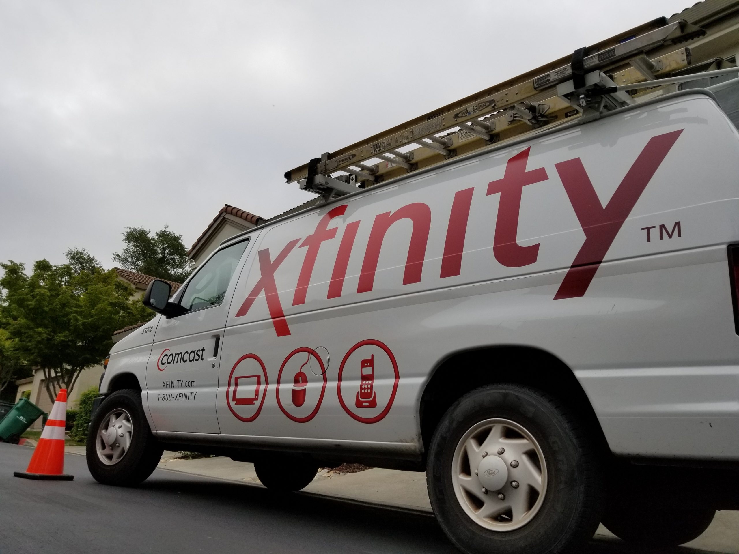 Low angle view of Comcast Xfinity cable television installation truck parked on a street in front of a suburban home.