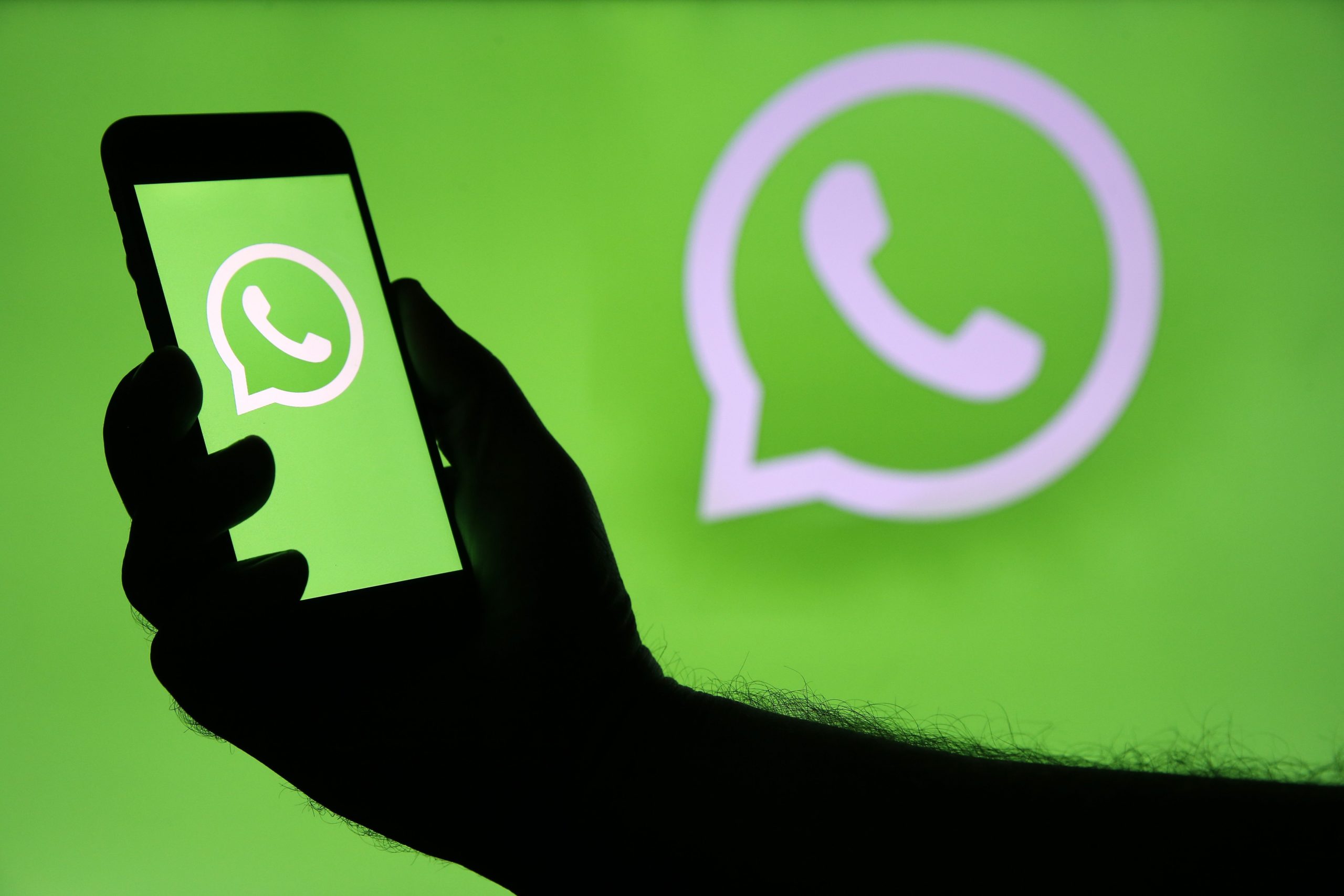 the WhatsApp logo and a hand with a smartphone using the app