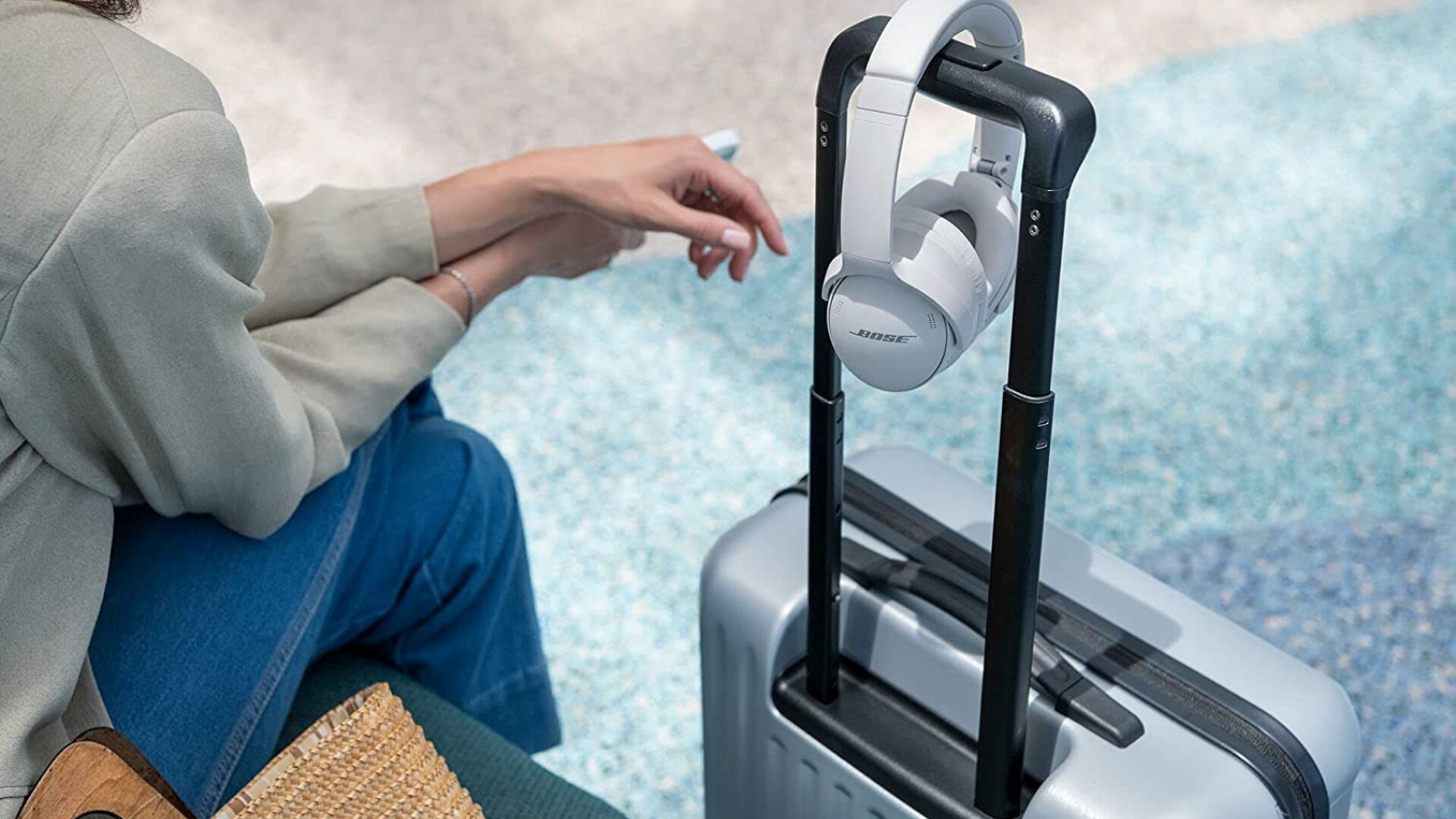 person sitting at airport with suitcase and bose quietcomfort 45 headphones