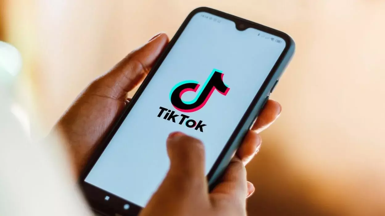 A person holding a phone with the TikTok logo on it.