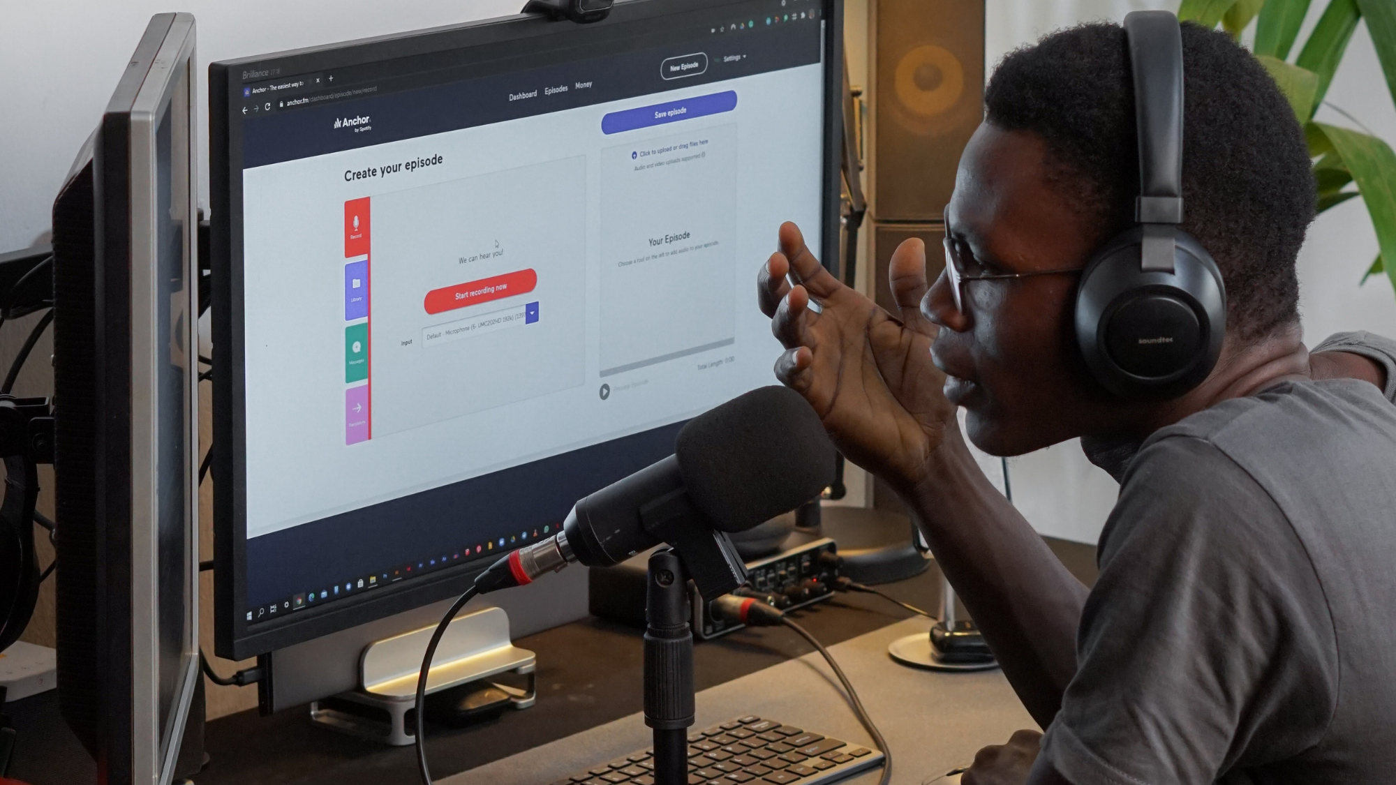 man talking into microphone in front of computer 