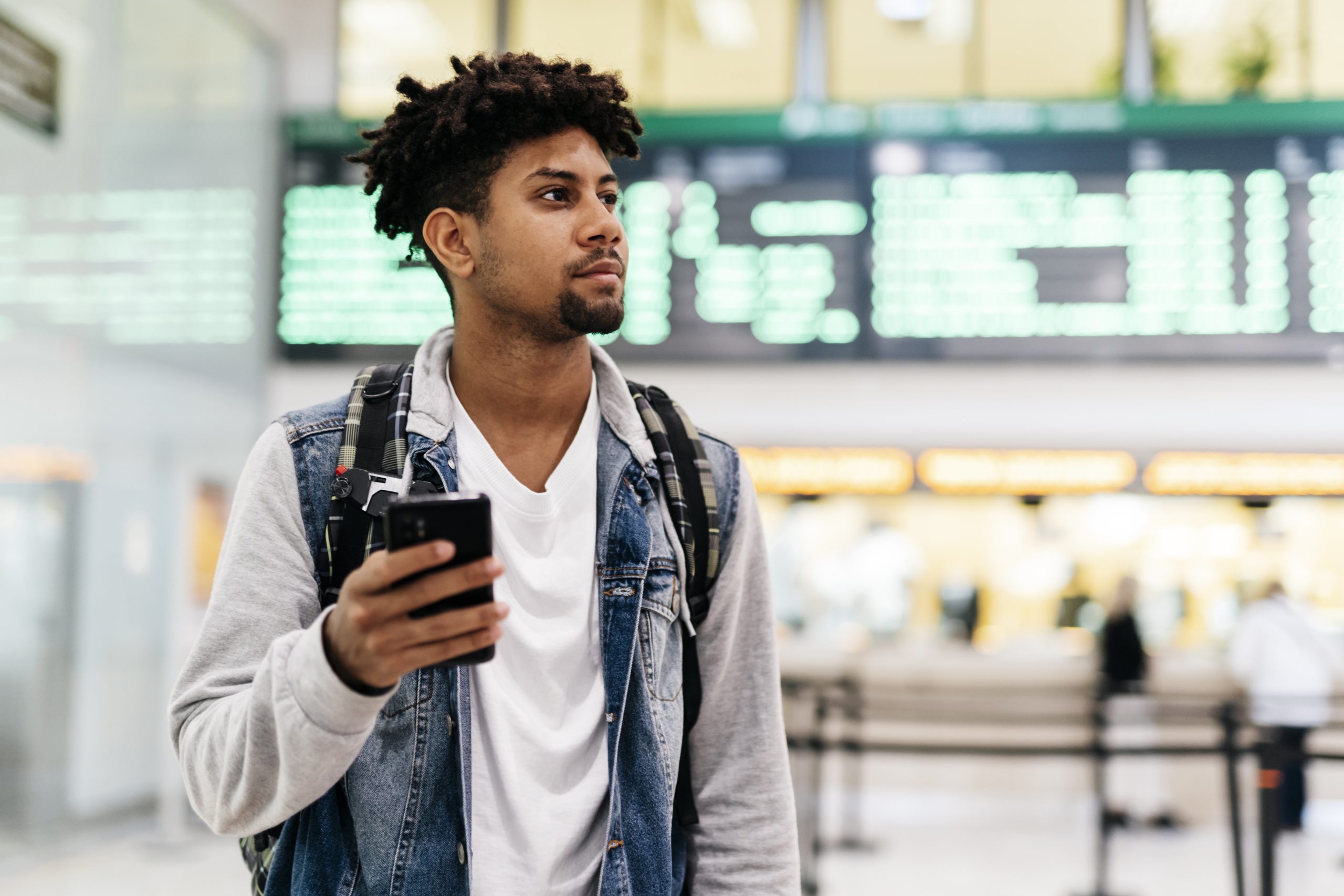 Man holding a phone while being in an airport.