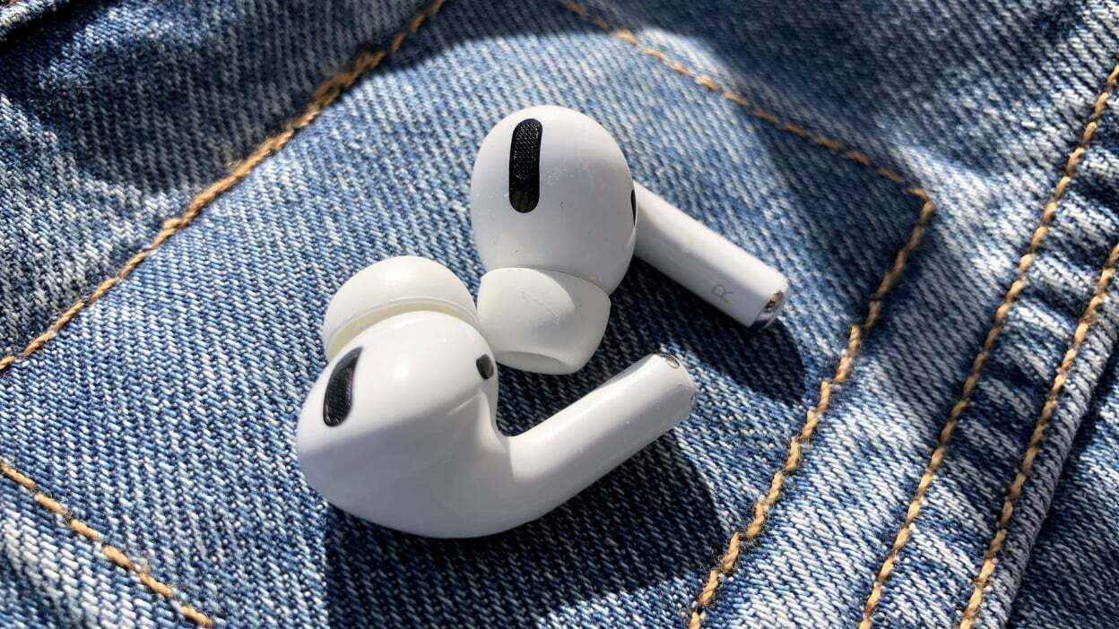 A pair of Apple AirPods Pro lying on denim material in the sun.