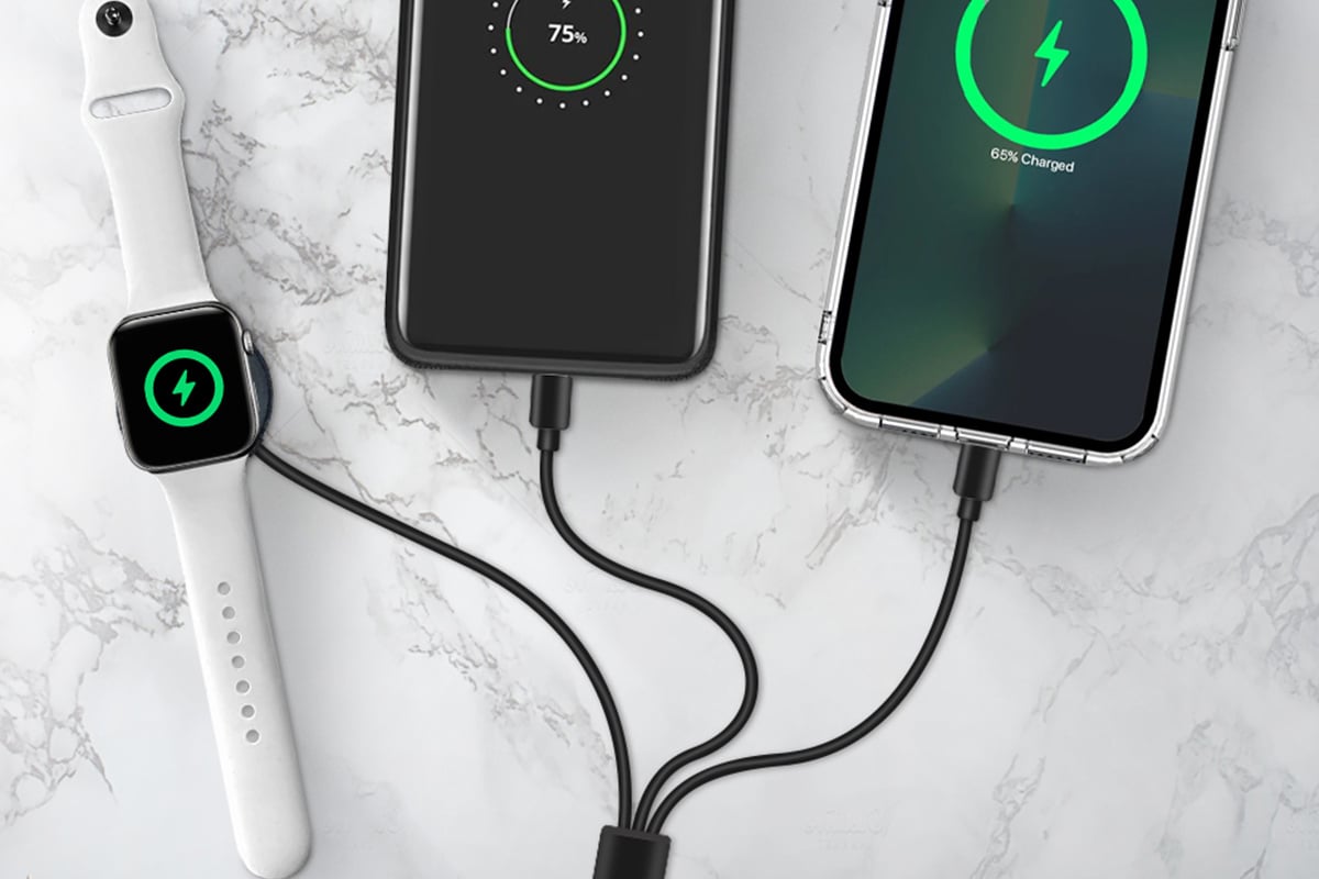 Apple devices charging with the help of a 3-in-1 cable on a marble counter.