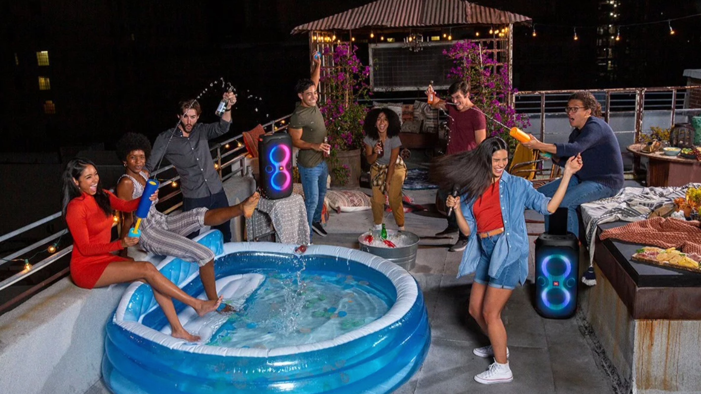 group of people around an inflatable blue pool and two JBL speakers