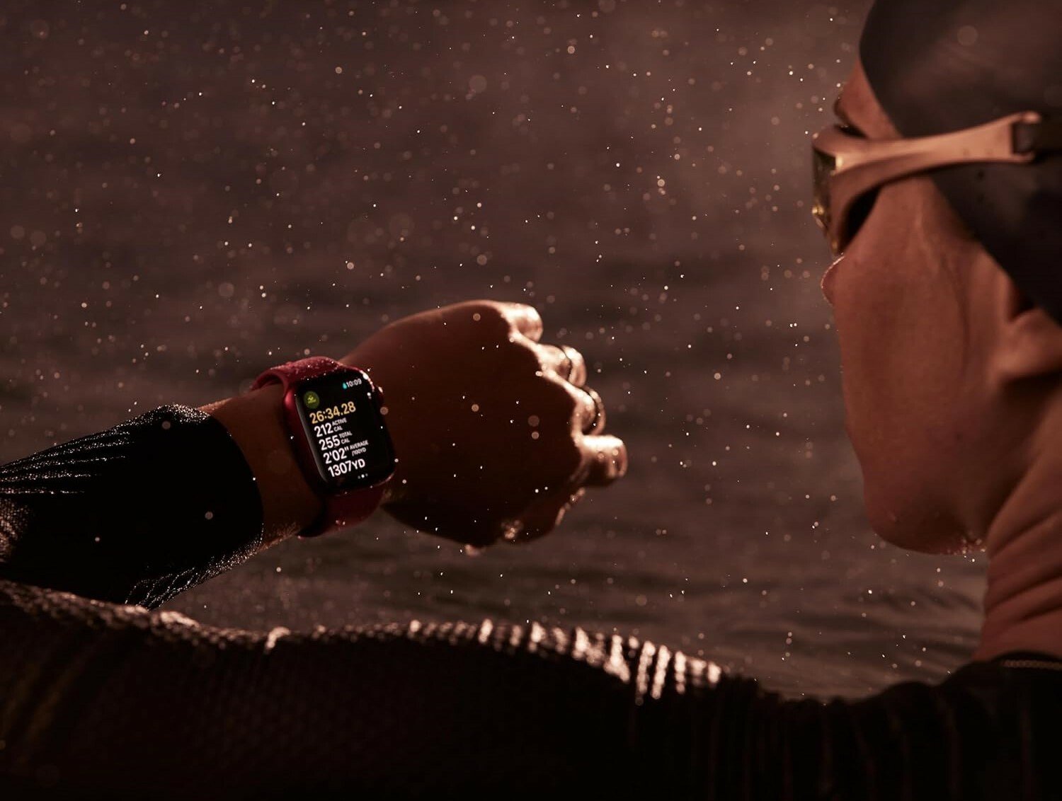 A swimmer in the water looks at her left wrist wearing an apple watch series 9