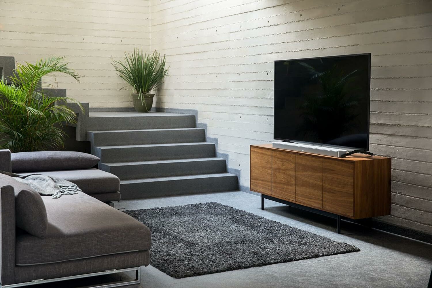 a white Bose Smart Soundbar 900 sits on an entertainment center in a sunken living room