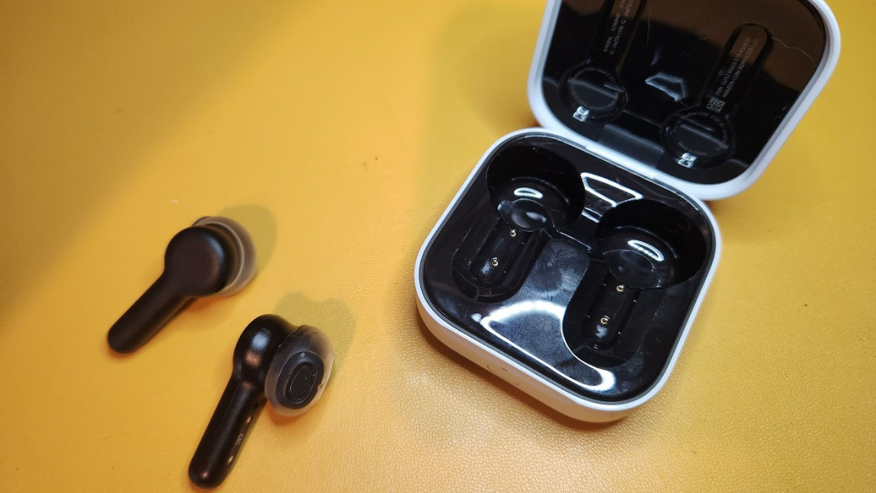 earbuds with stems and their case against a yellow background