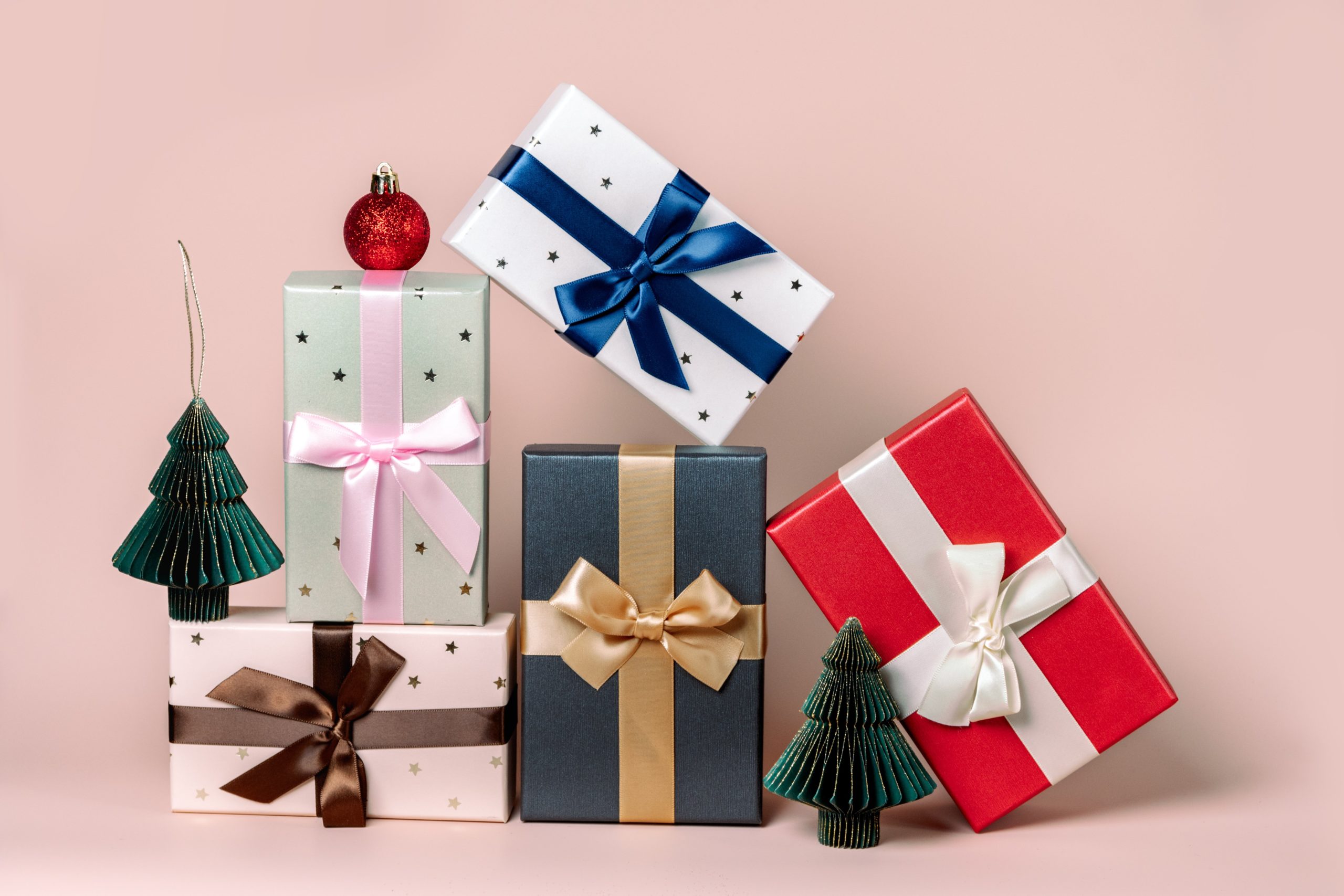 five decoratively wrapped packages sit in front of a pink background