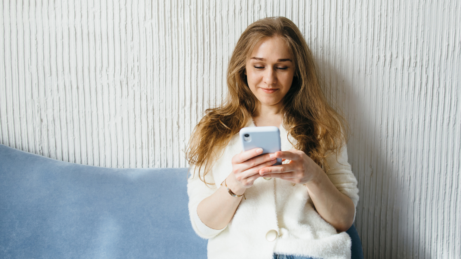 Young woman with mobile phone relaxing on sofa at home