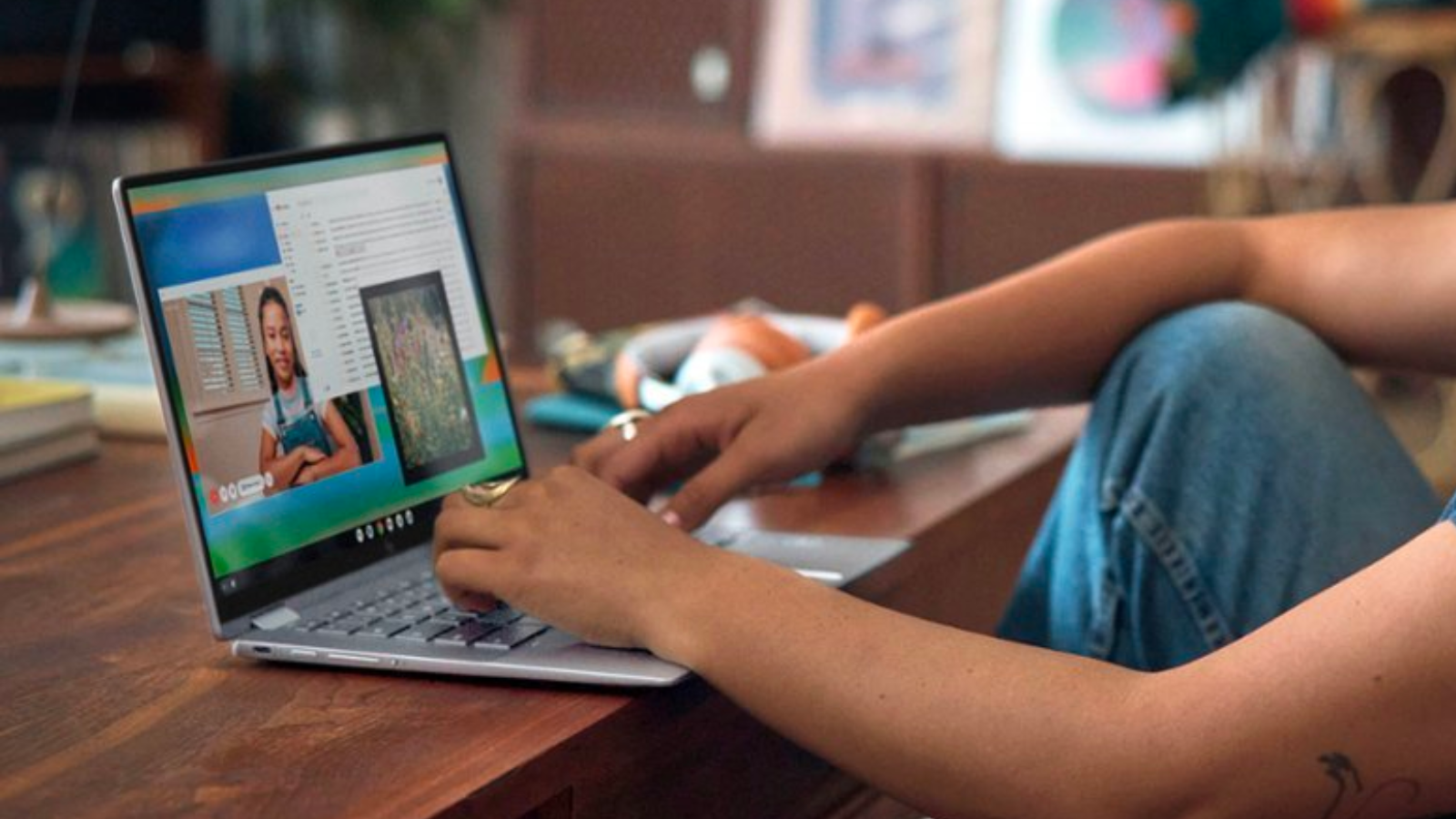 a close-up of a person touching the trackpad of a dell xps 15 laptop while sitting at a wooden table