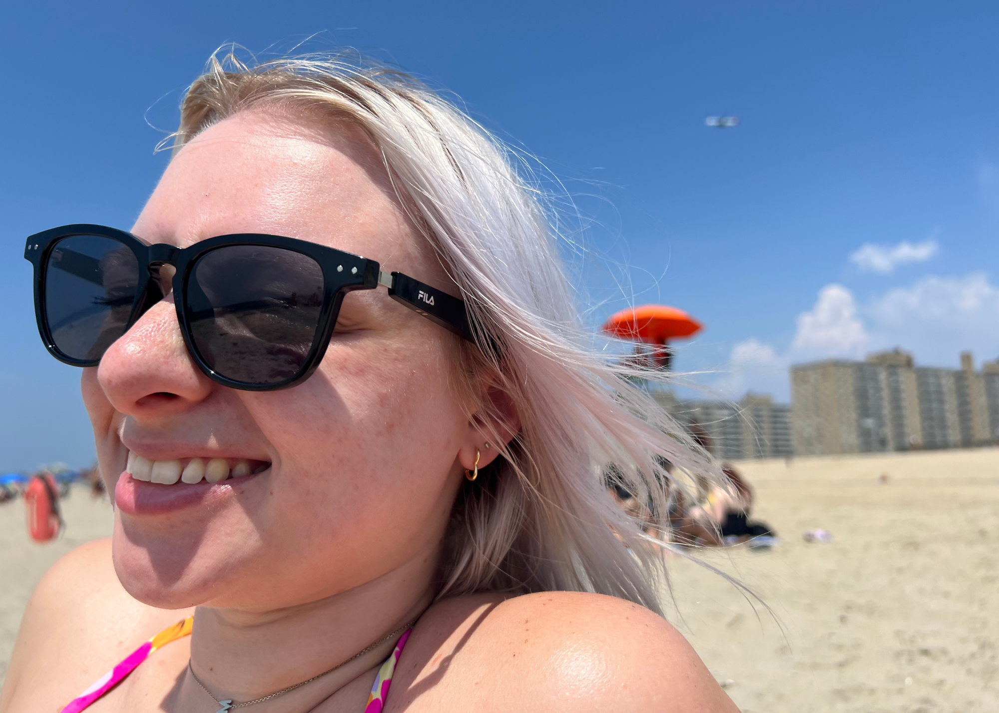 woman at the beach wearing black fila sunglasess