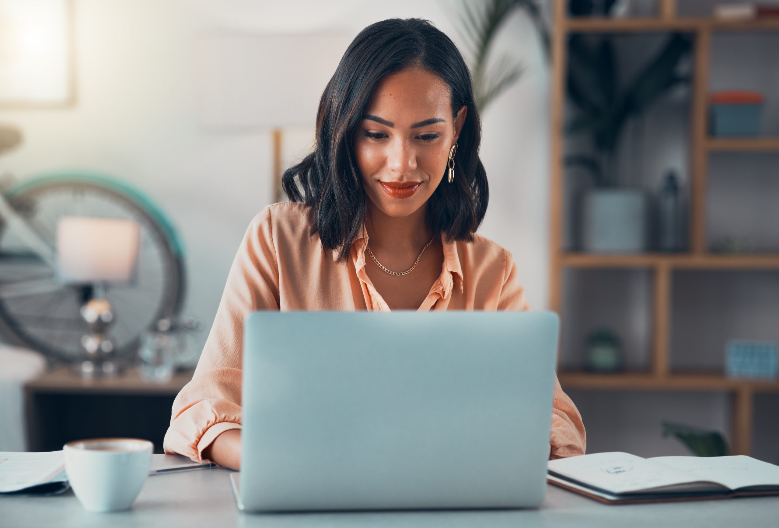 Woman smiles while looking at laptop.