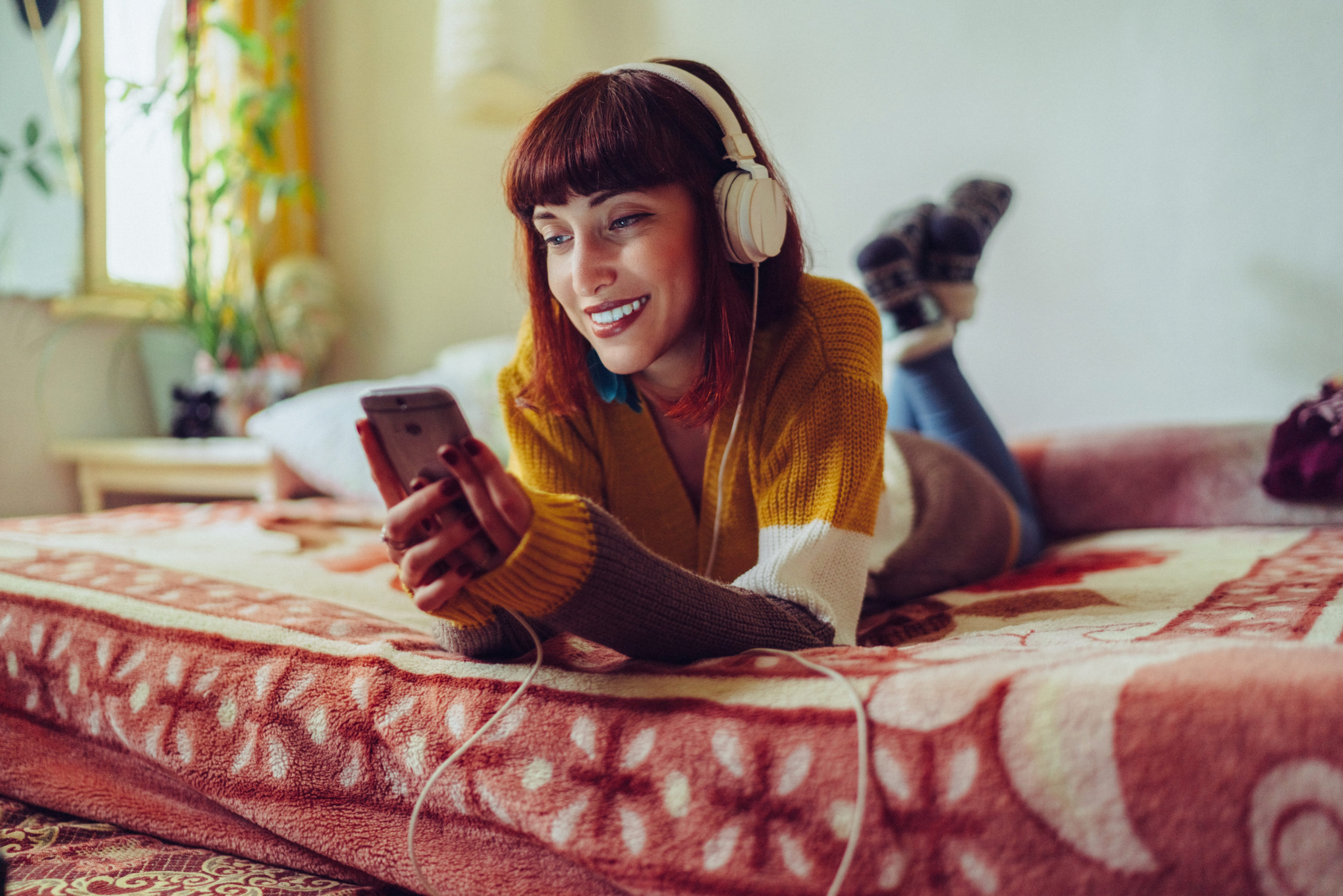 woman laying on bed listening to audiobook