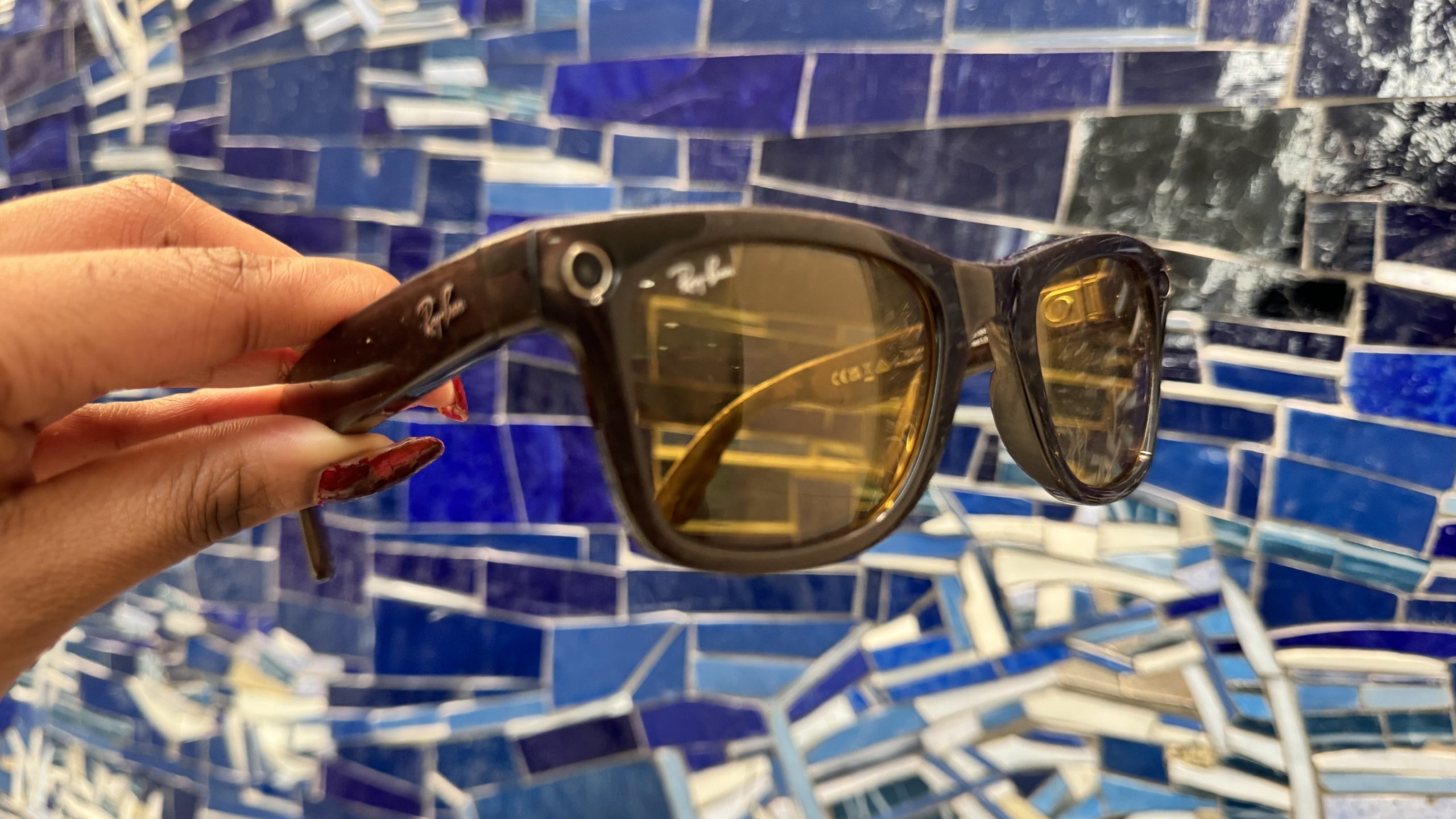 Ray-Ban Meta Smart Glasses in front of a wall with varying hues of blue