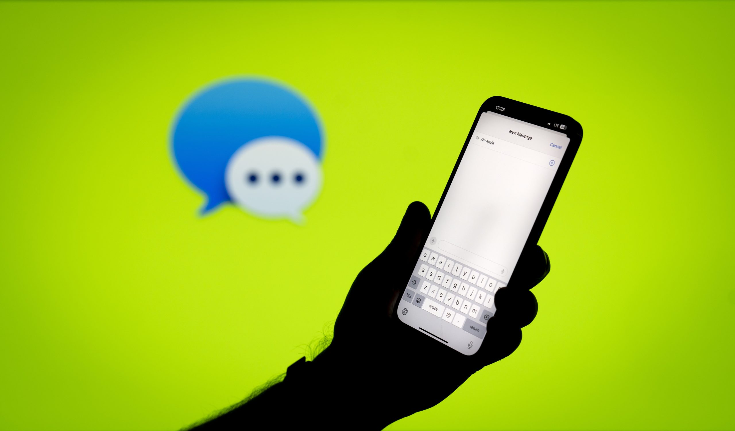 Apple iMessage app open on phone in front of green backdrop with iMessage logo