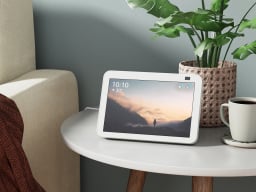 The Amazon Echo Show 8 (3rd Gen) in Glacier White on an end table next to a couch.