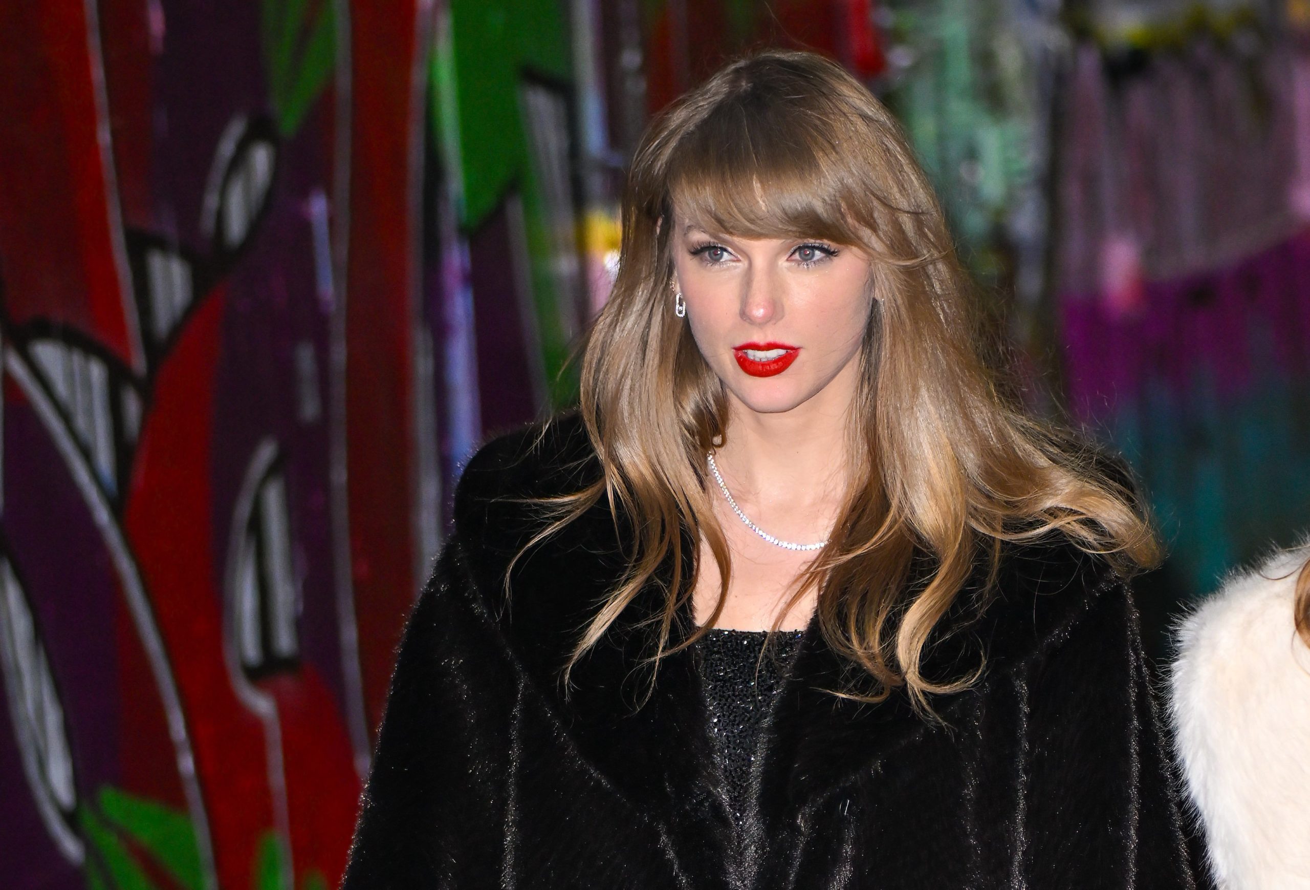 top half of taylor swift wearing fuzzy black coat