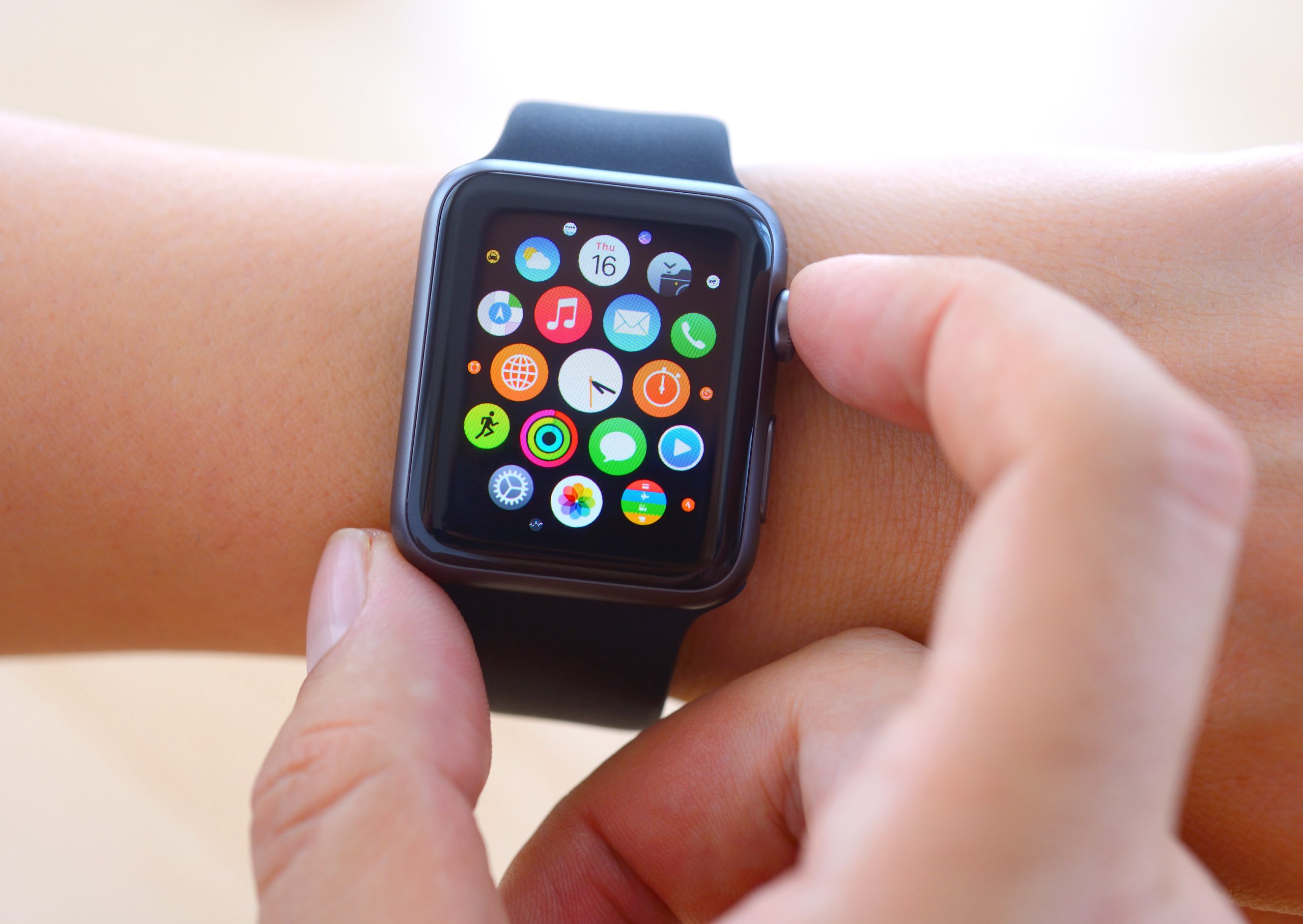 Hand touching an Apple Watch displaying home screen