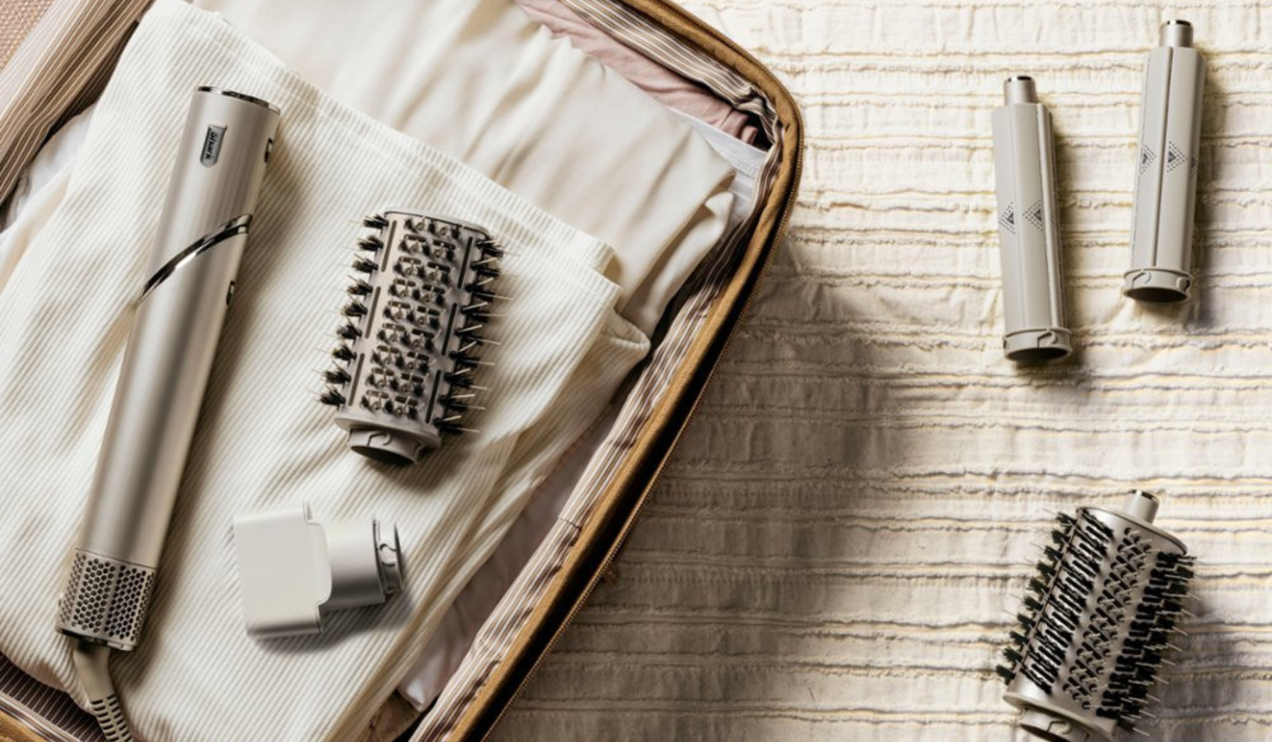 Shark FlexStyle hair styler handle and attachments laying on bed and suitcase