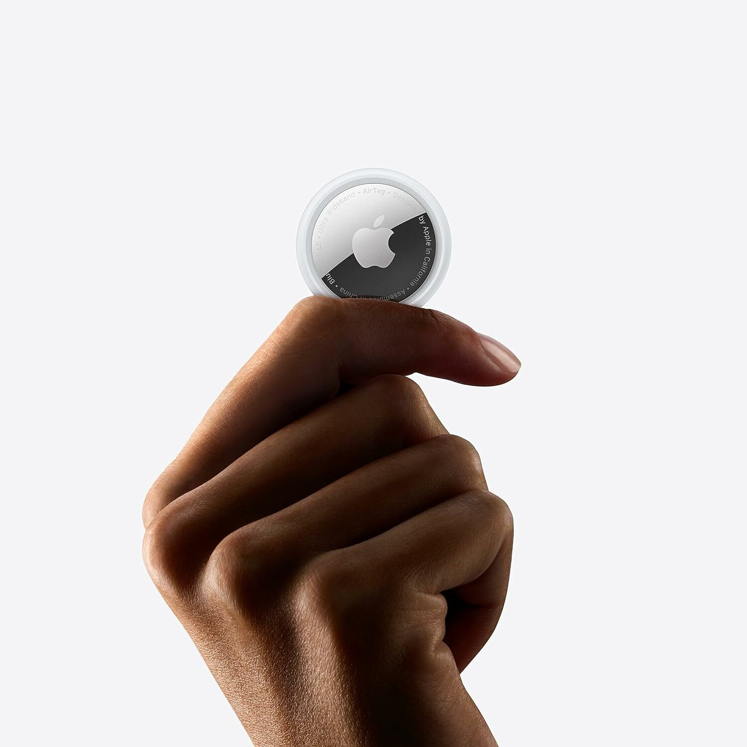 A hand holds up an Apple AirTag