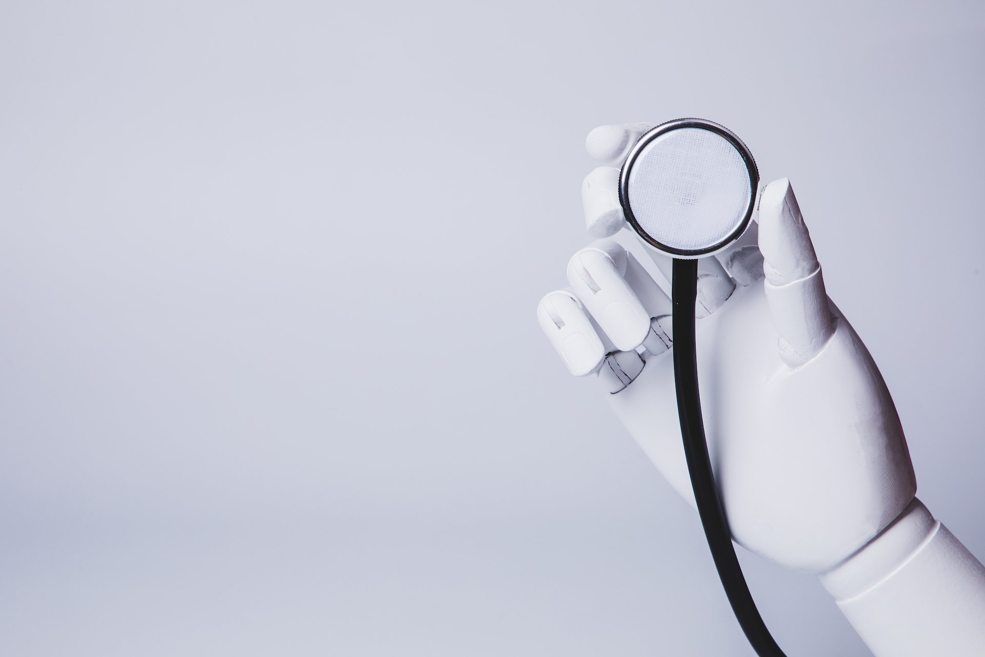 A robot hand holds a magnifying glass.