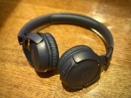 The JBL Tune 510BT headphones in dark blue lying on a wooden floor