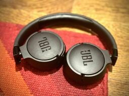 The JBL Tune 660NC headphones lying on a red rug on wooden floor