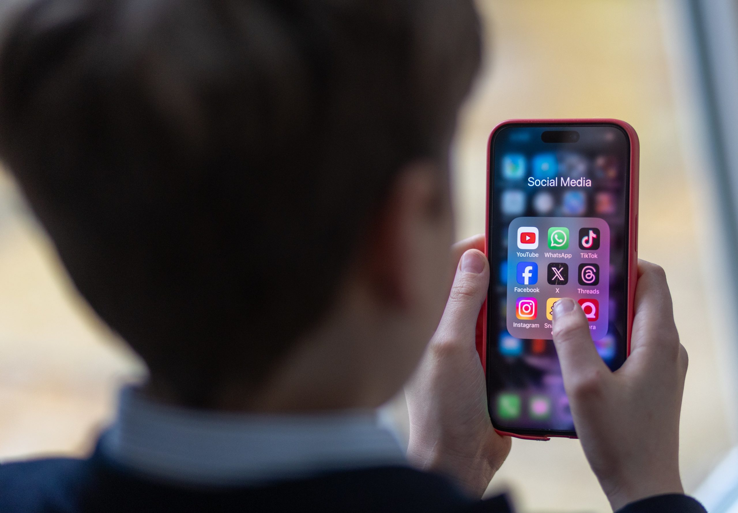 A 12-year-old boy looks at an iPhone screen showing various social media apps including TikTok, Facebook and X on February 25, 2024 in Bath, England. This week the UK government issued new guidance backing headteachers in prohibiting the use of mobile phones throughout the school day, including at break times. Many schools around the country are already prohibiting mobile phone use over concerns. The amount of time children spend on screens each day rocketed during the Covid pandemic by more than 50 per cent, the equivalent of an extra hour and twenty minutes. Researchers say that unmoderated screen time can have long-lasting effects on a child's mental and physical health. Recently TikTok announced that every account belonging to a user below age 18 have a 60-minute daily screen time limit automatically set.